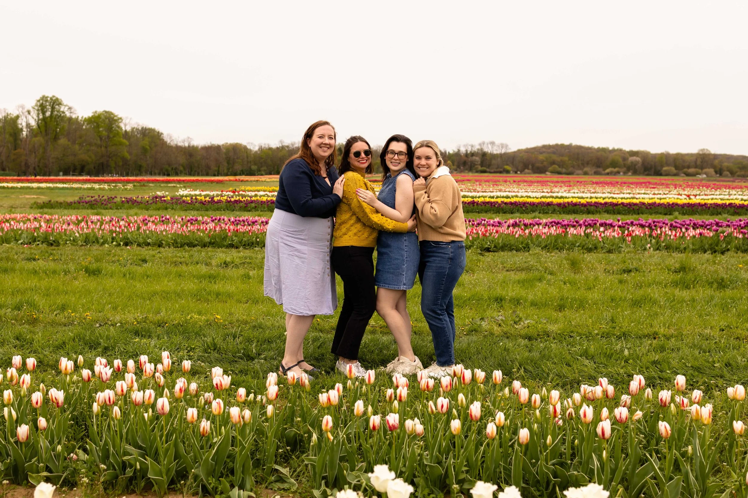 Four friends pose in a tulip field in spring - best friends portrait taken by Jennifer Fulton Photography in Bucks County, PA