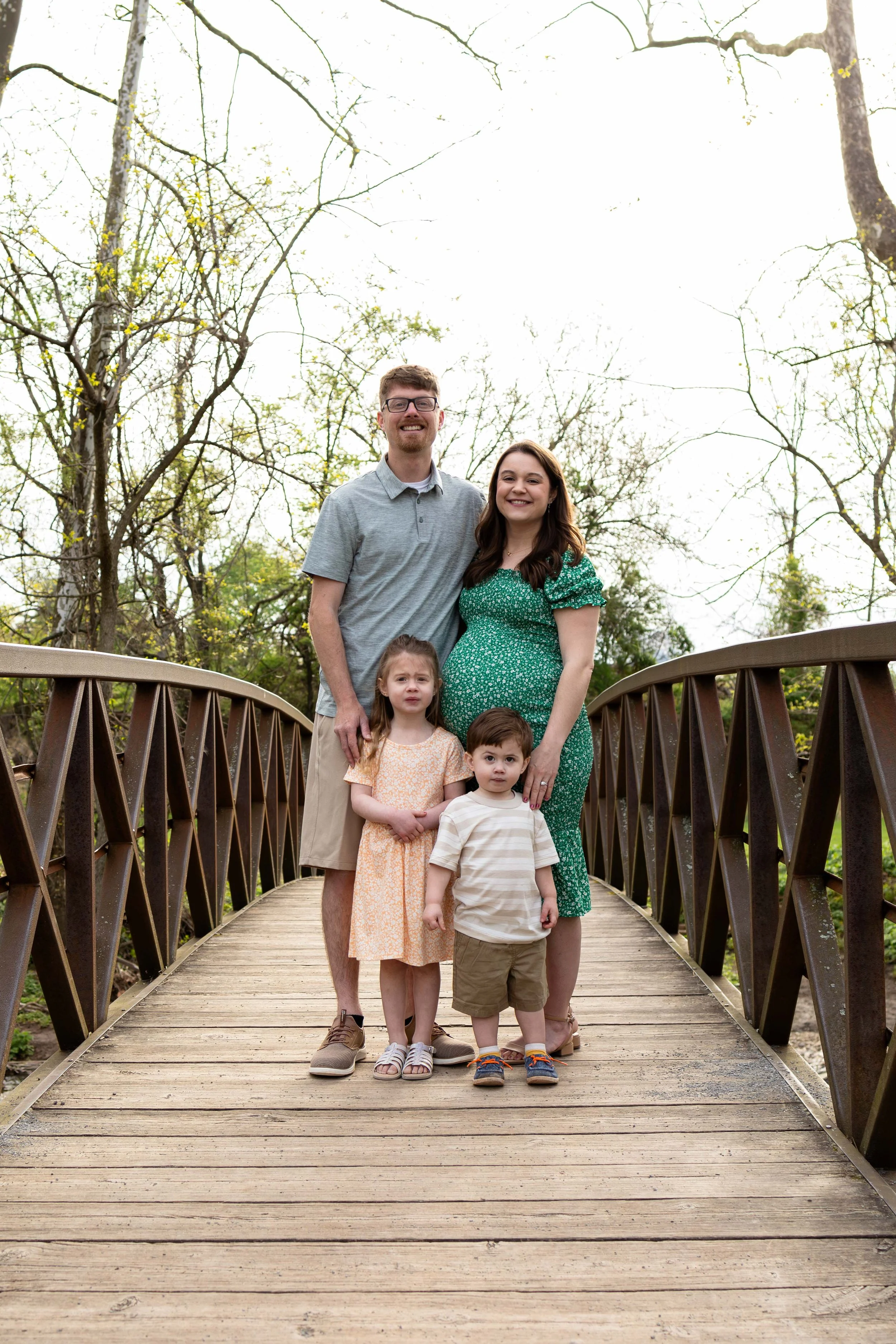 A young family stands on a bridge - maternity portrait taken by Jennifer Fulton Photography in Central NJ