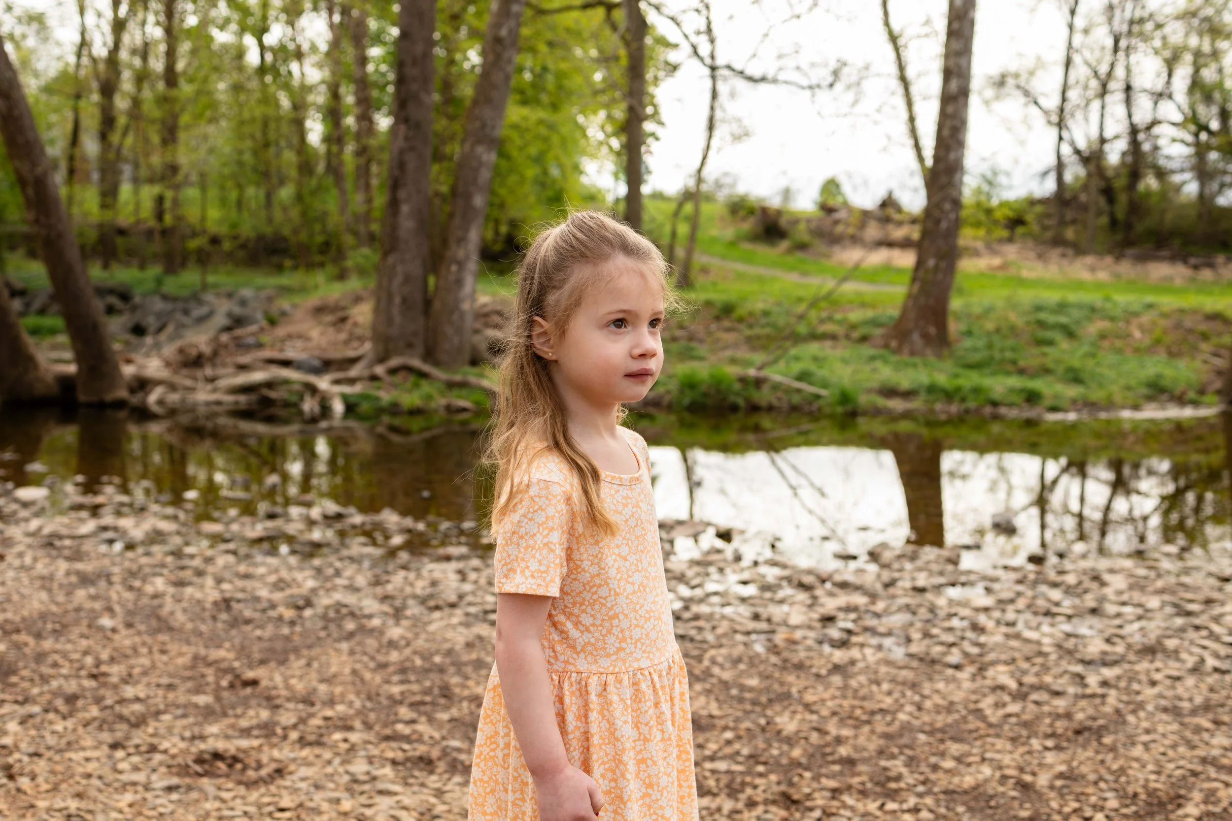 A young girl stands near a creek in spring - maternity portrait taken by Jennifer Fulton Photography in New Jersey