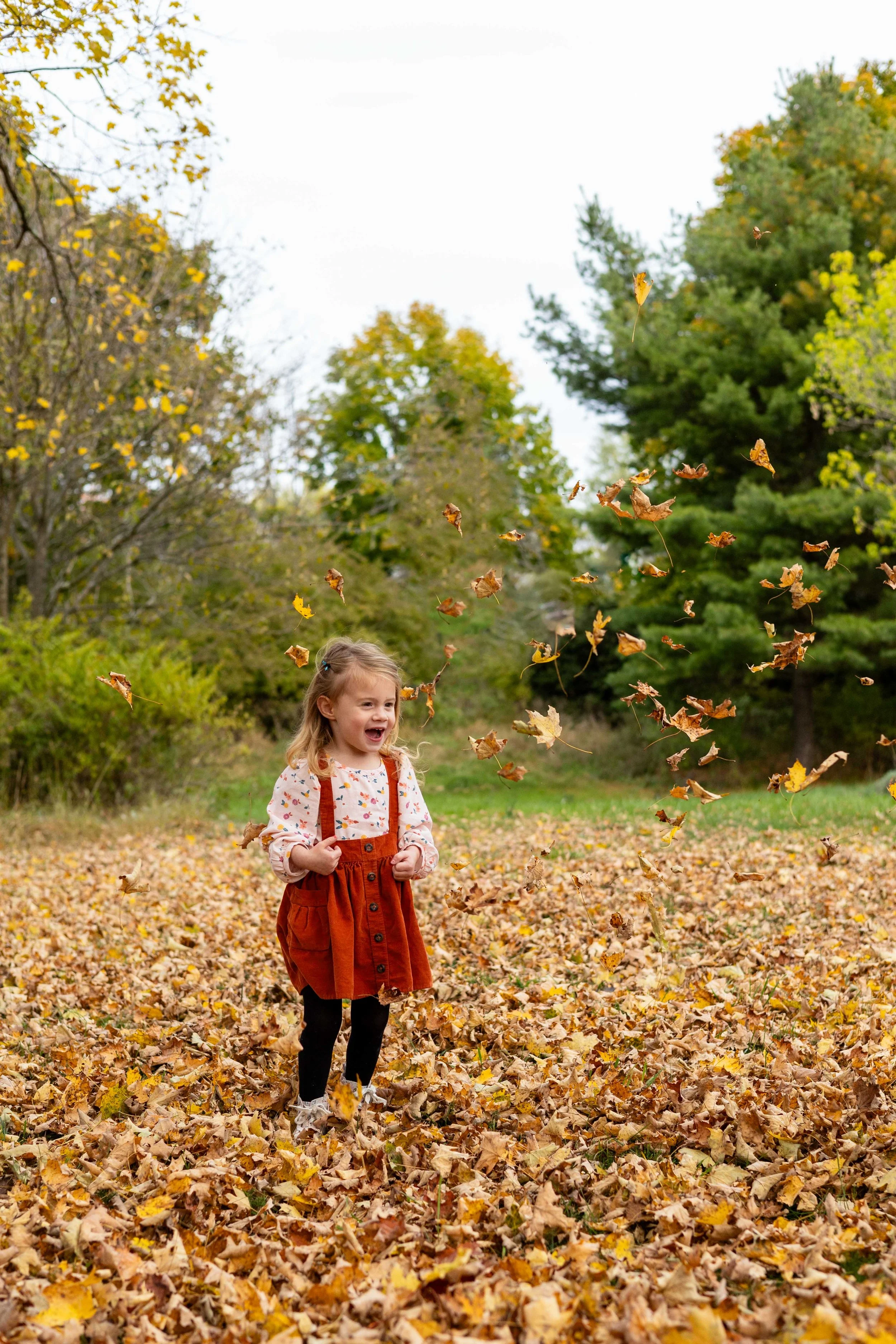 A young girl throws yellow leaves in the air and laughs - taken in Hunterdon County, New Jersey by Jennifer Fulton Photography