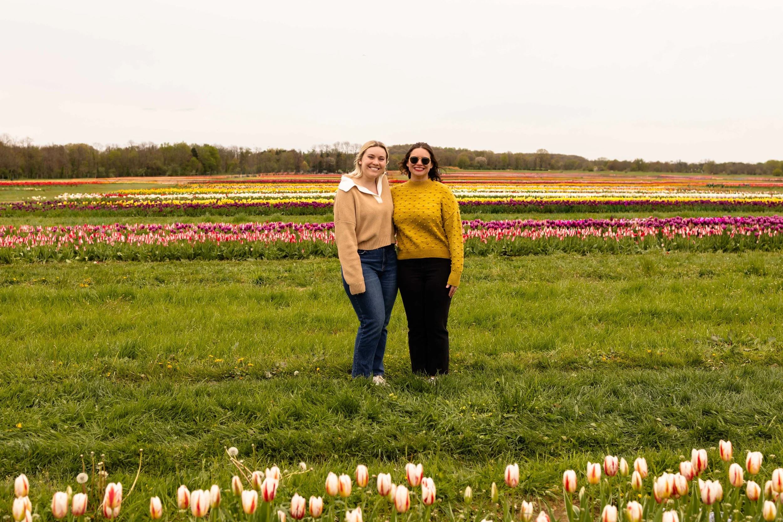 Two friends pose in a flower field in spring - best friends photo taken by Jennifer Fulton Photography in Central NJ