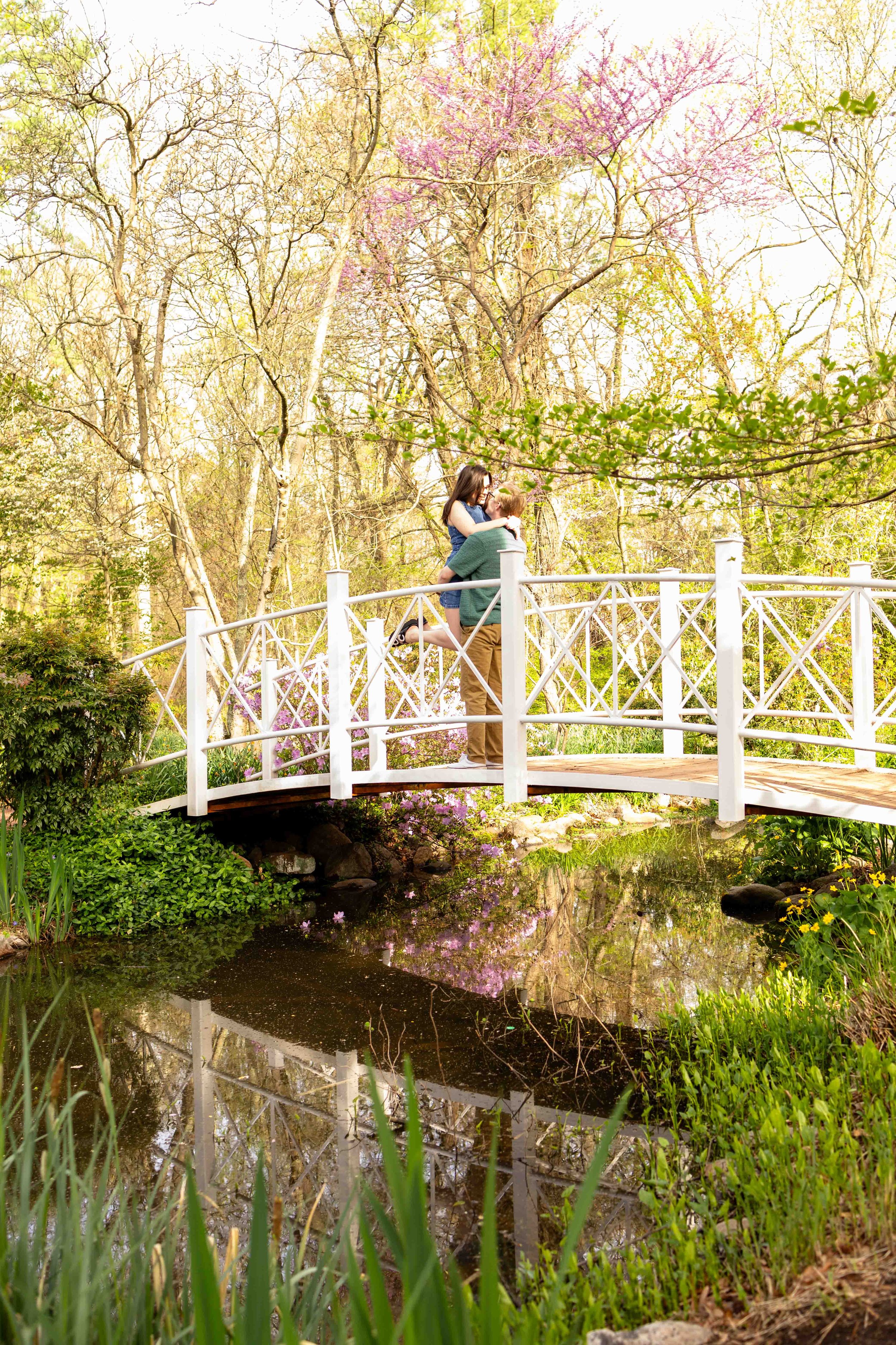 A couple embraces on a bridge in a garden - couple's engagement photo taken by Jennifer Fulton Photography in Hopewell, NJ