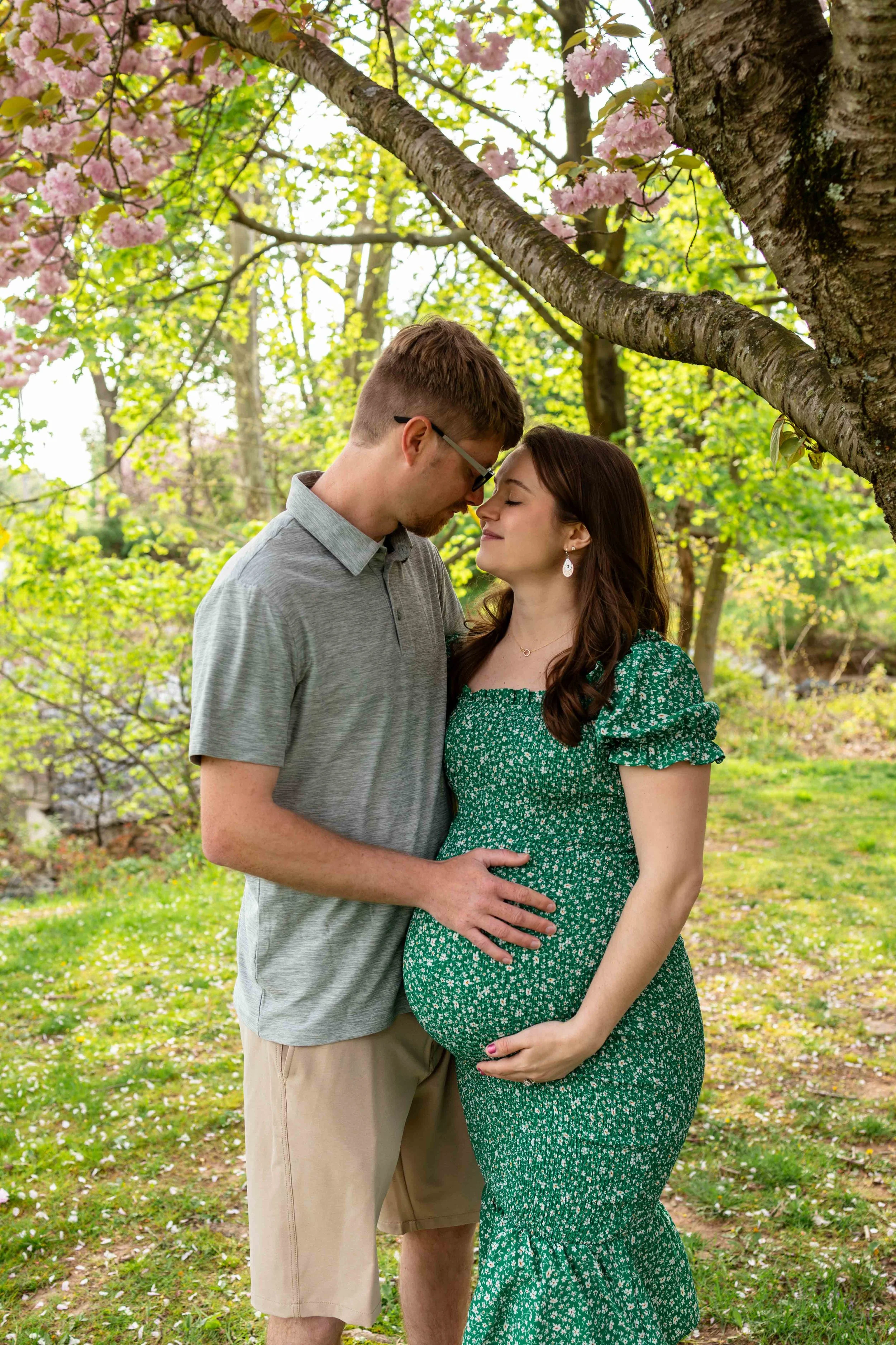 An expecting couple embraces under a cherry tree - maternity portrait taken by Jennifer Fulton Photography in Tewksbury, NJ