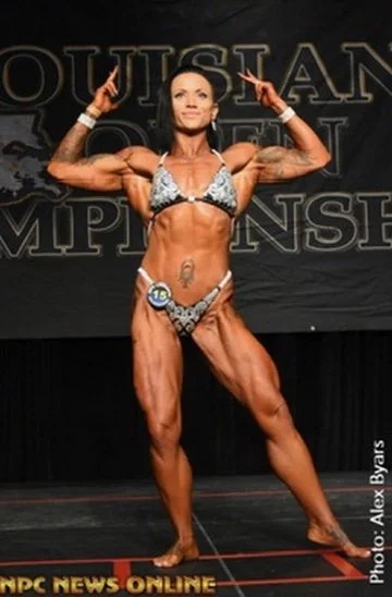 Female bodybuilder posing on stage at a bodybuilding championship event.