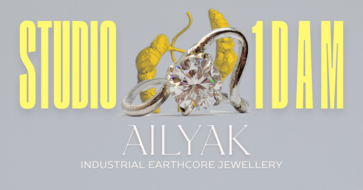 A promotional graphic for Studio I Dam featuring jewelry with large text, yellow roots, and a silver ring with a diamond, along with the name 'Ailyak' and the description 'Industrial Earthcore Jewelry'