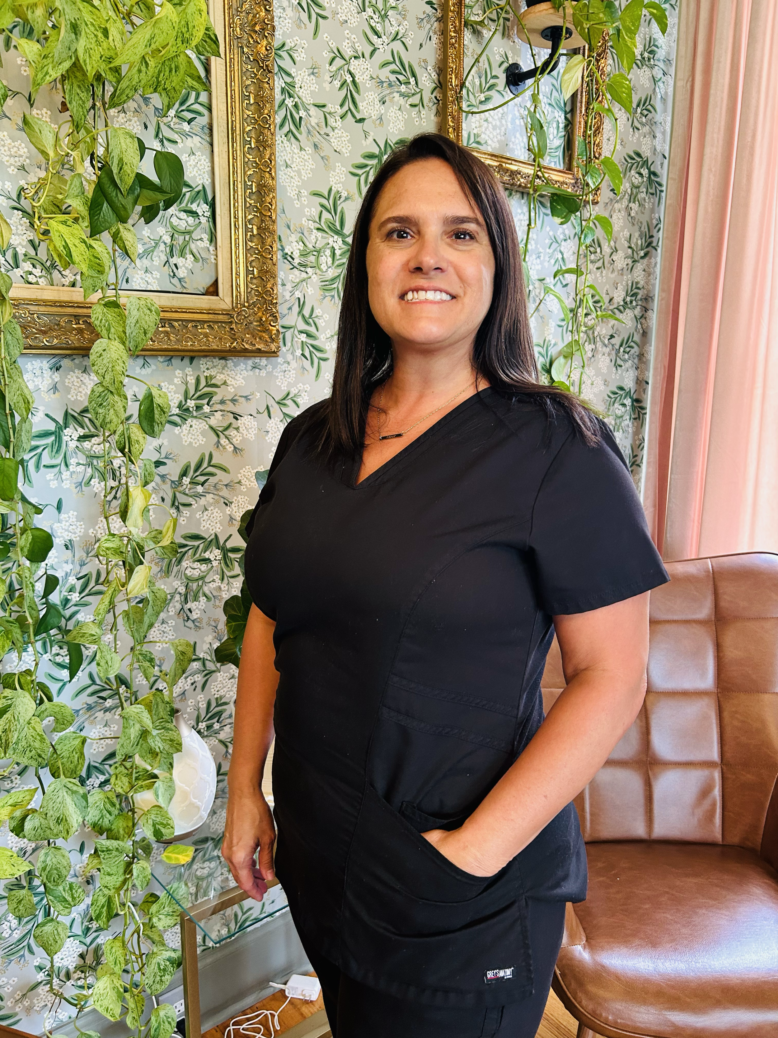 Woman in scrubs standing in front of a flowered wall in a wellness center
