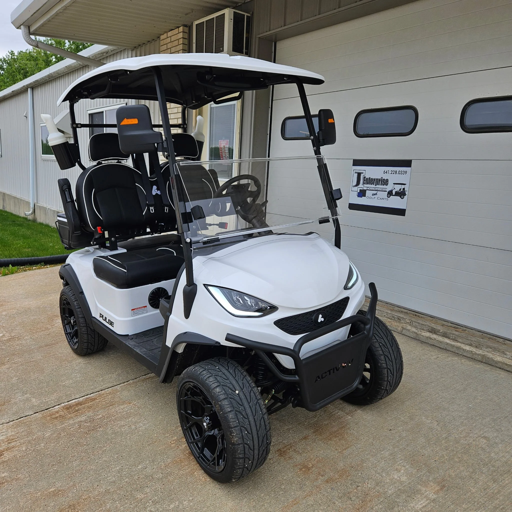 Gray Bintelli electric golf cart with black seats and a transparent windshield.