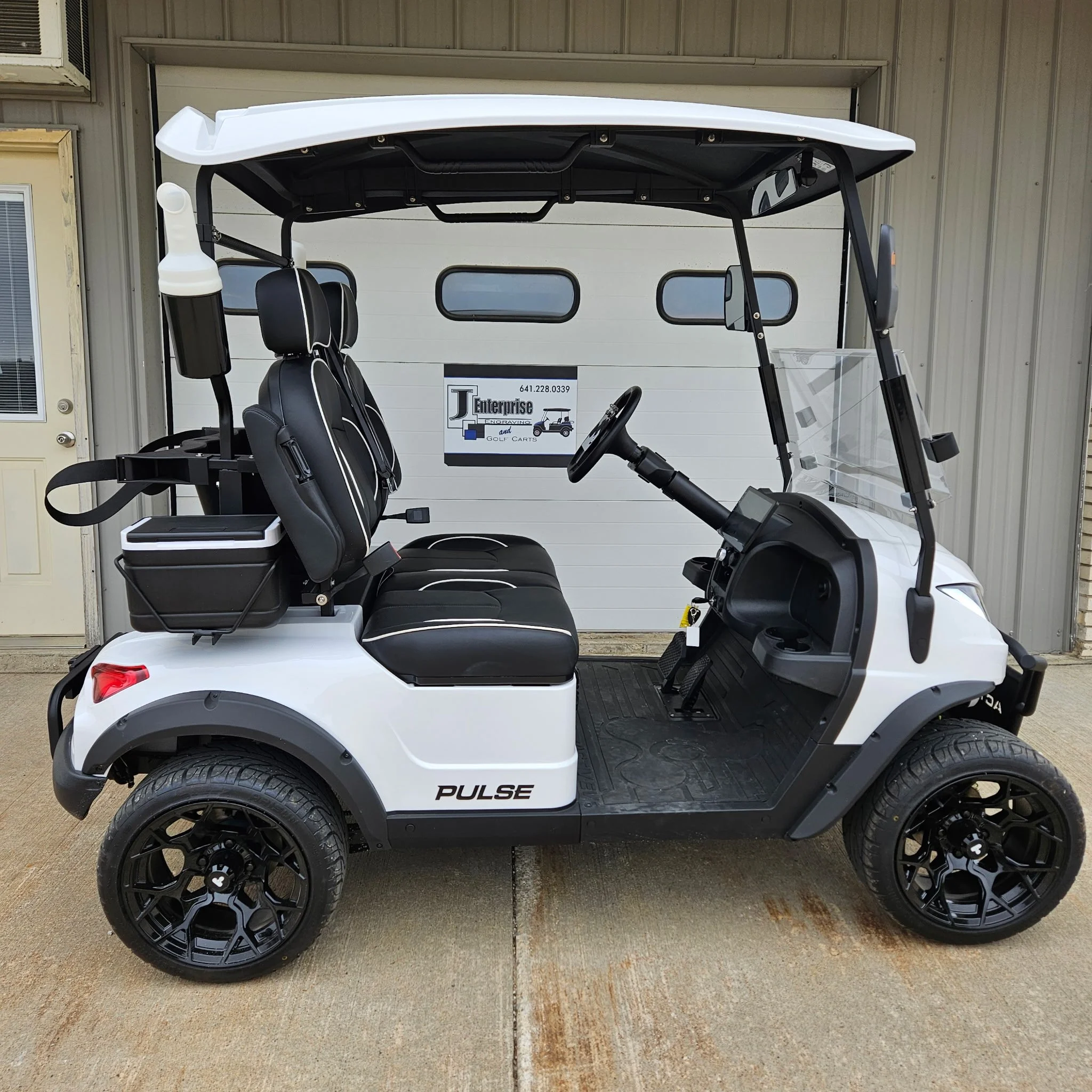 Close-up of a golf cart seat with steering wheel and additional seating.