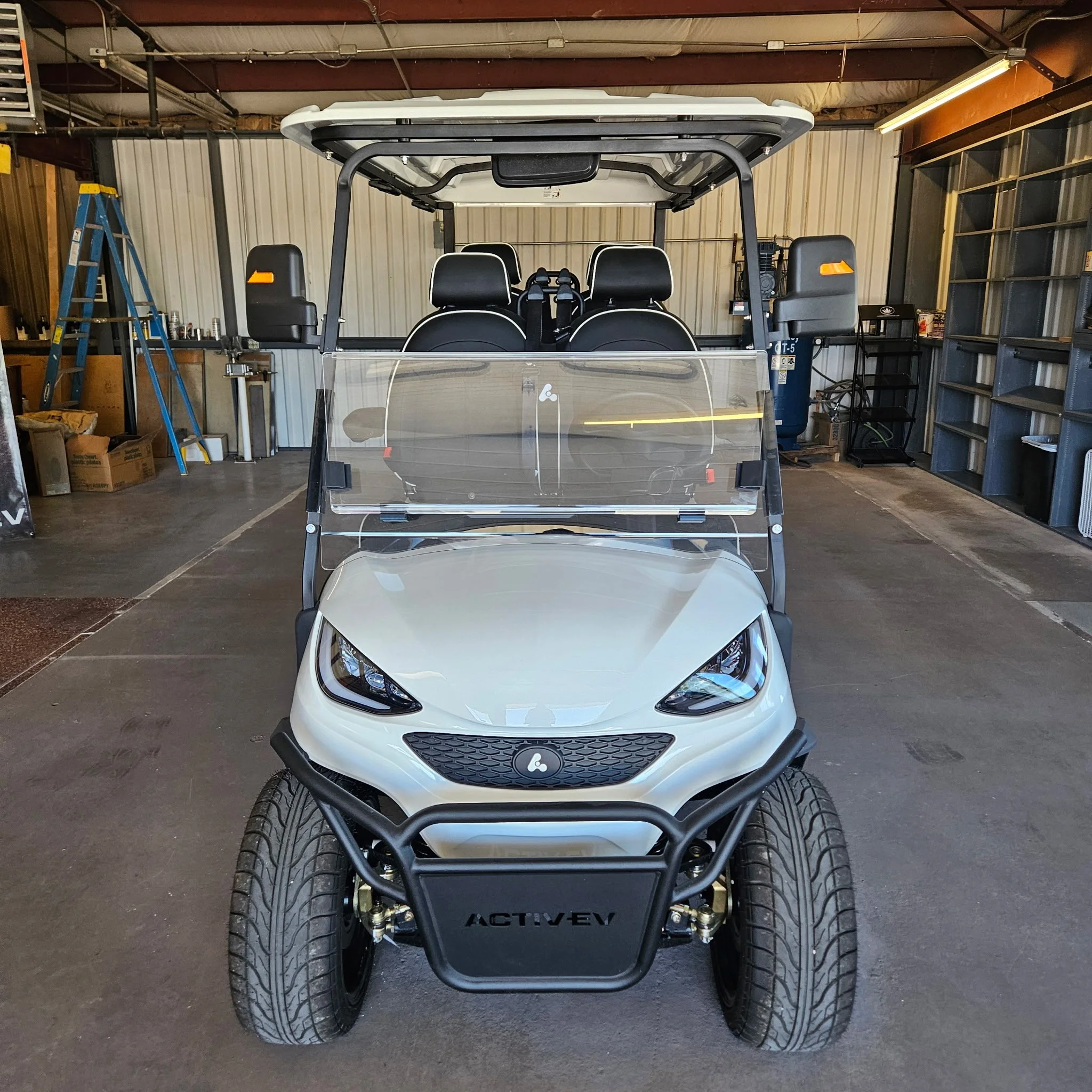 Close-up of a golf cart seat with steering wheel and additional seating.