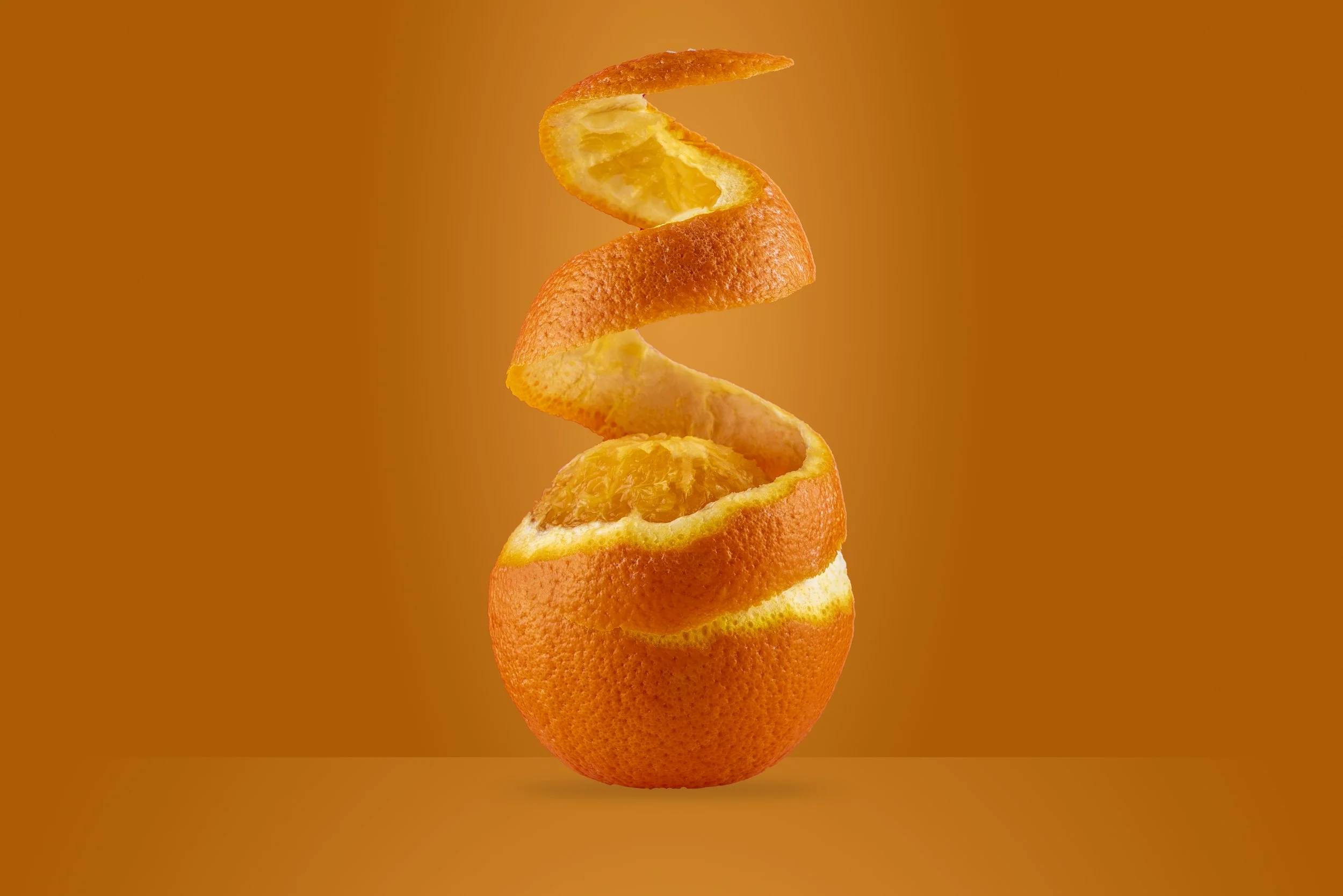 Peeled orange with spiral peel on brown background