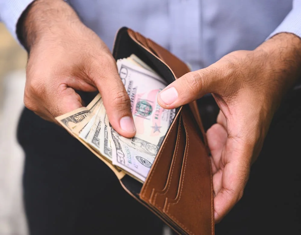 Hands holding open a wallet with cash inside