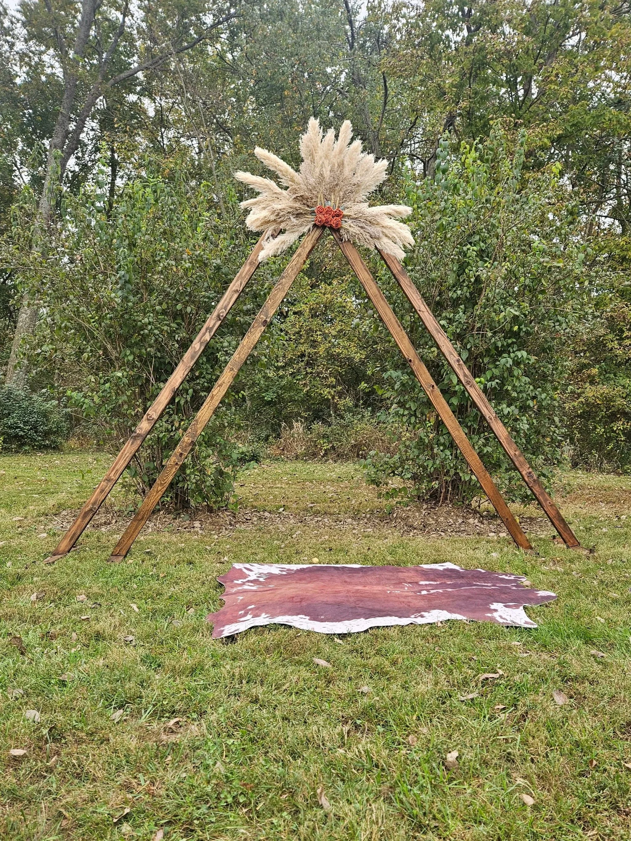 Cow hide mat laying infront of brown wooden wedding arch