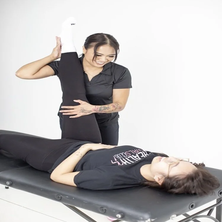 Physical therapist stretching a patient's leg on a treatment table.