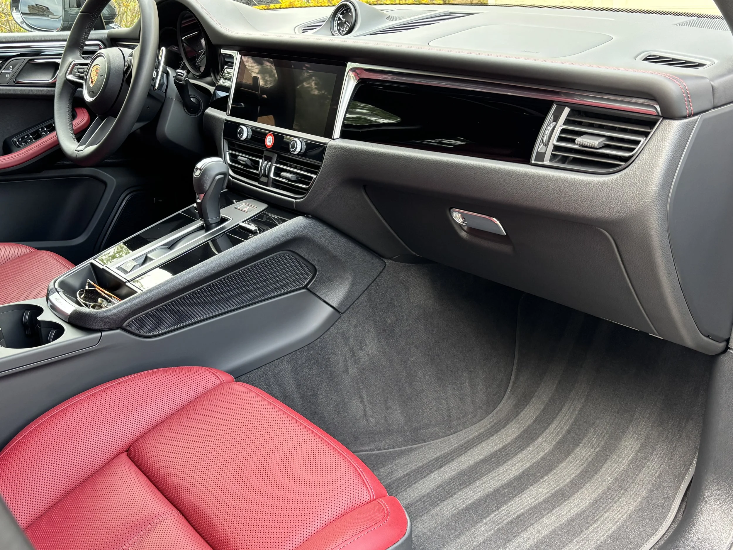 Close-up of black leather car seats with white stitching.