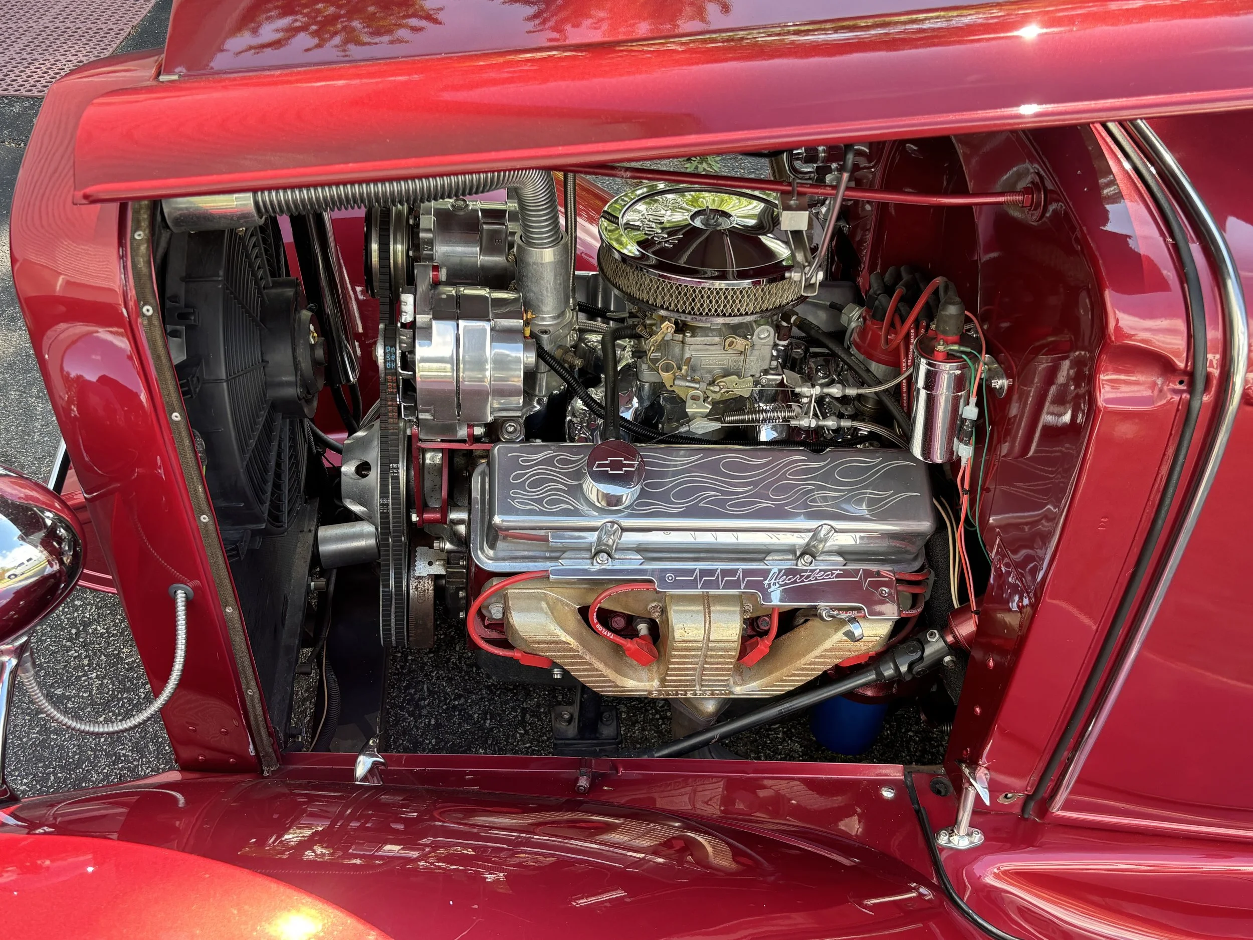 Close-up of a car engine with a person cleaning it using a yellow cloth.