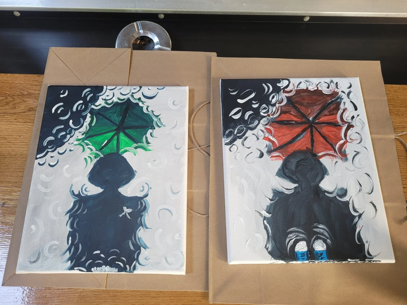 Two paintings of a person sitting in the rain holding an umbrella. The left one has a green umbrella, and the right one has a red umbrella. Both paintings depict the person from behind, with the rain and clouds in the background.