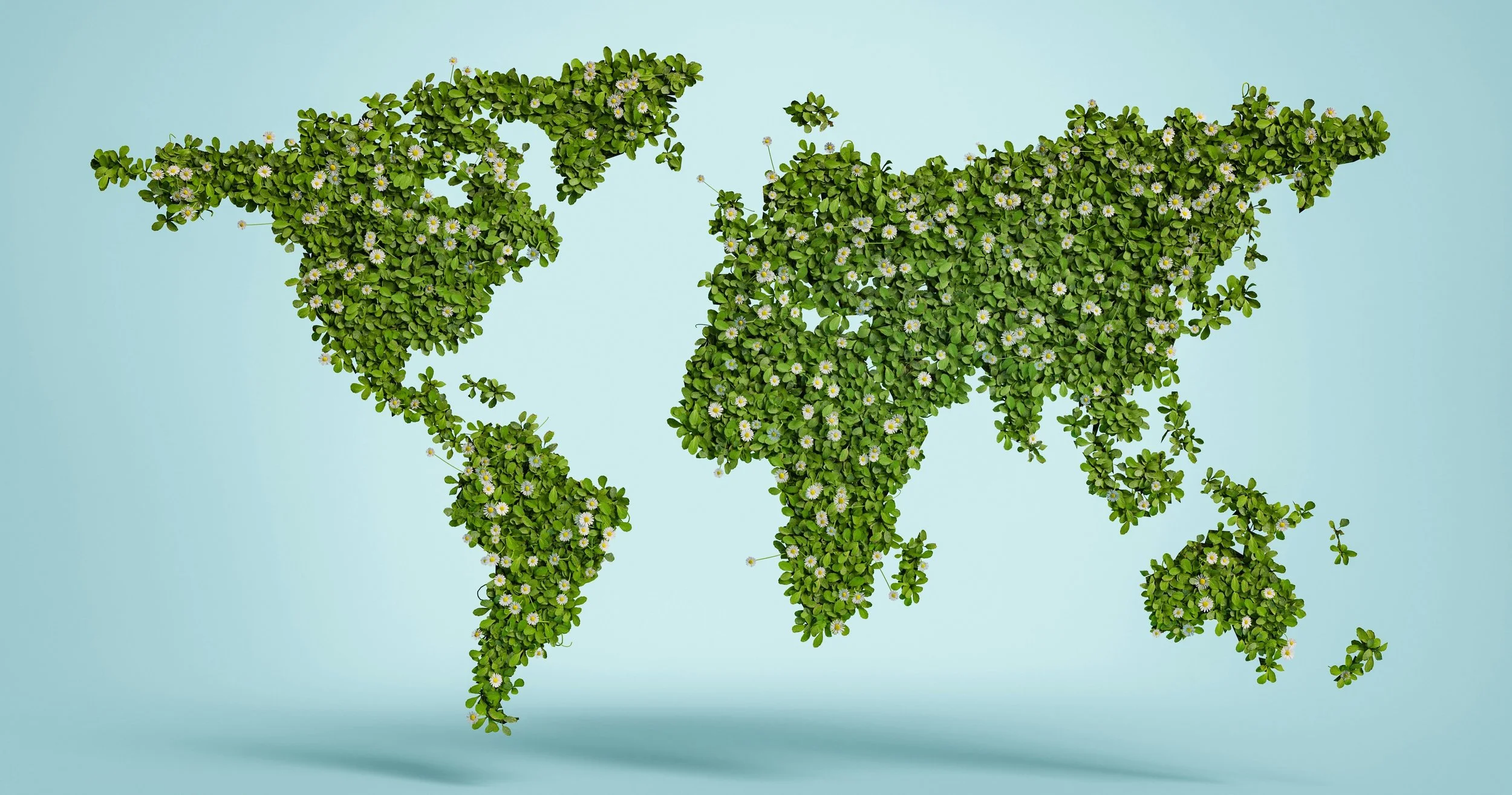 Map of the world shaped with green leaves and small white flowers on a light blue background.