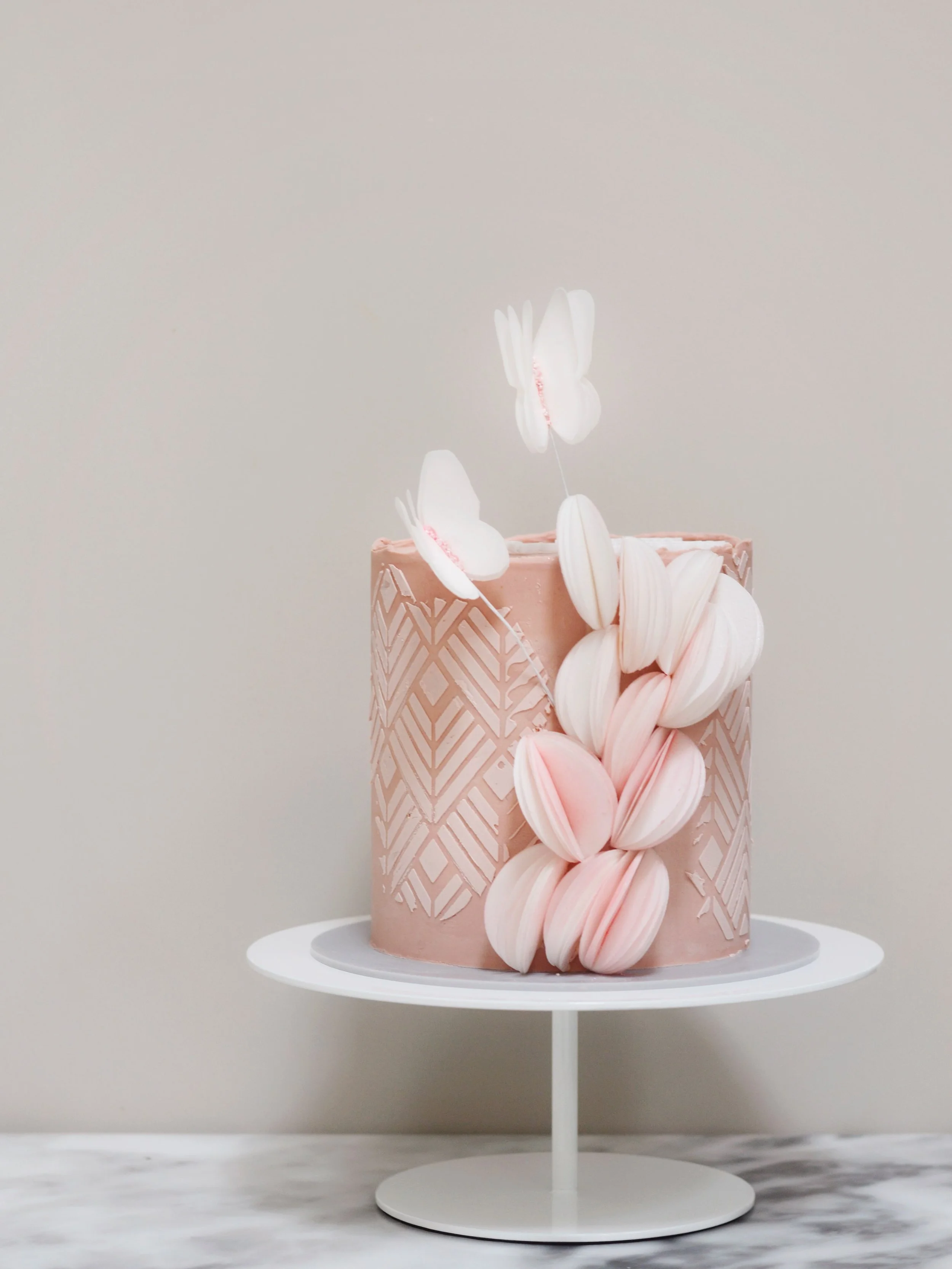 Two birthday cakes and I&rsquo;m using the same design language on both. 
A stencilled pattern and wafer paper spheres cascading down the side. 
The first is soft and playful, the second needed a wow factor so the same idea &ldquo;grew up&rdquo;a lit