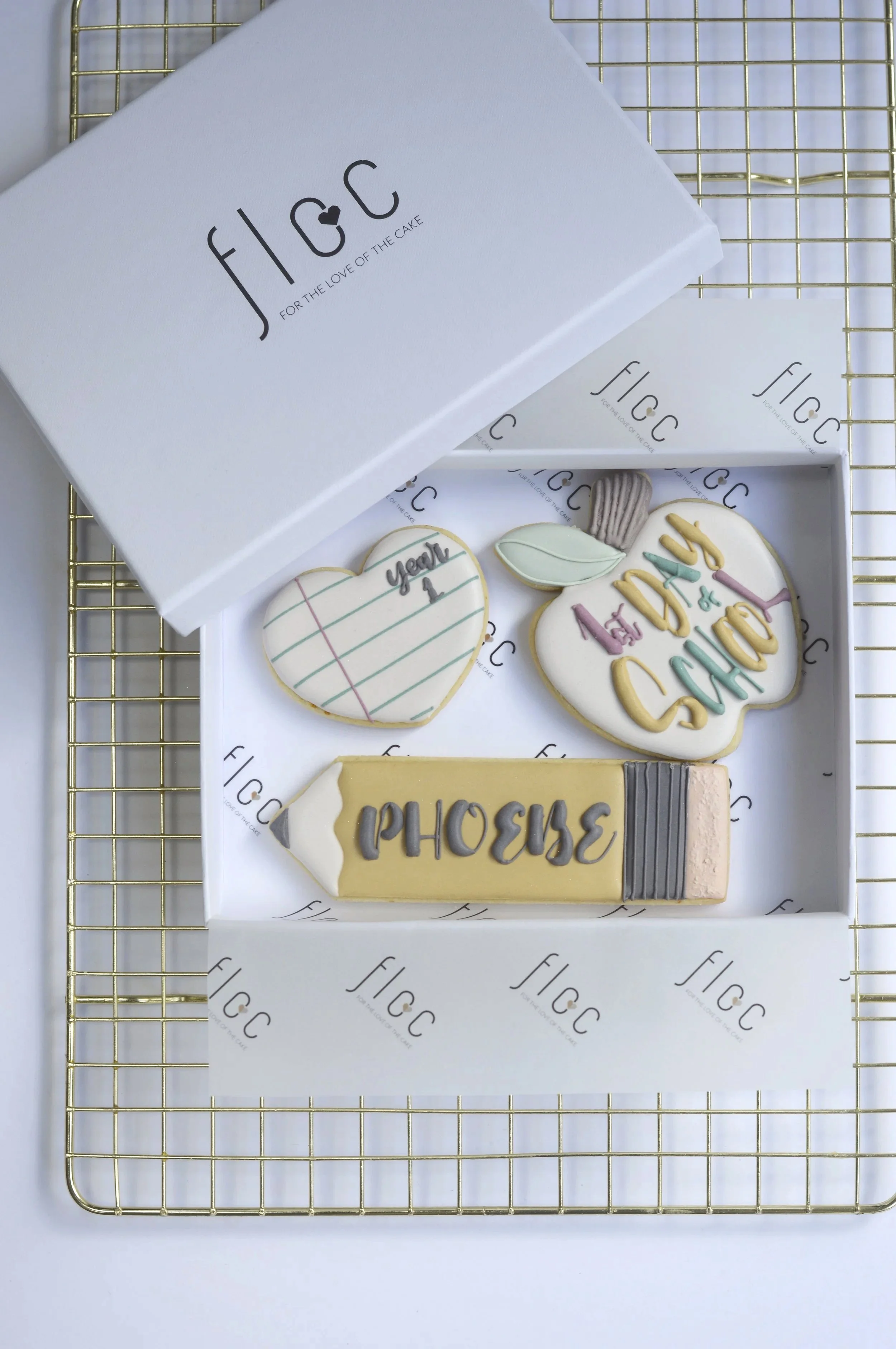 Overhead view of a personalised First Day of School cookie gift box by Floc Bakes with hand-piped apple, heart and pencil cookies
