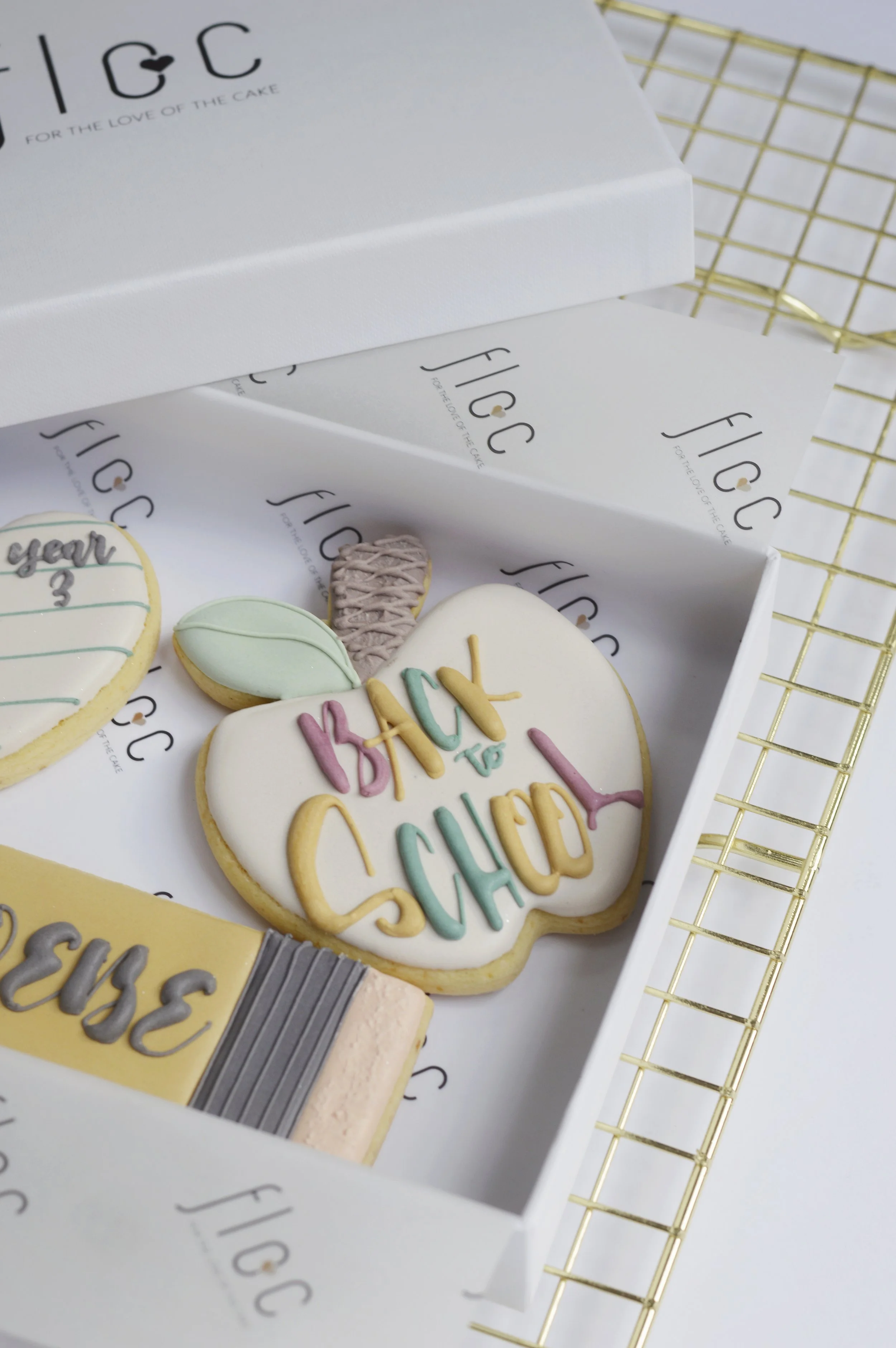 Hand-piped apple-shaped cookie reading "Back to School" in pastel icing, from Floc Bakes' personalised Back to School cookie box