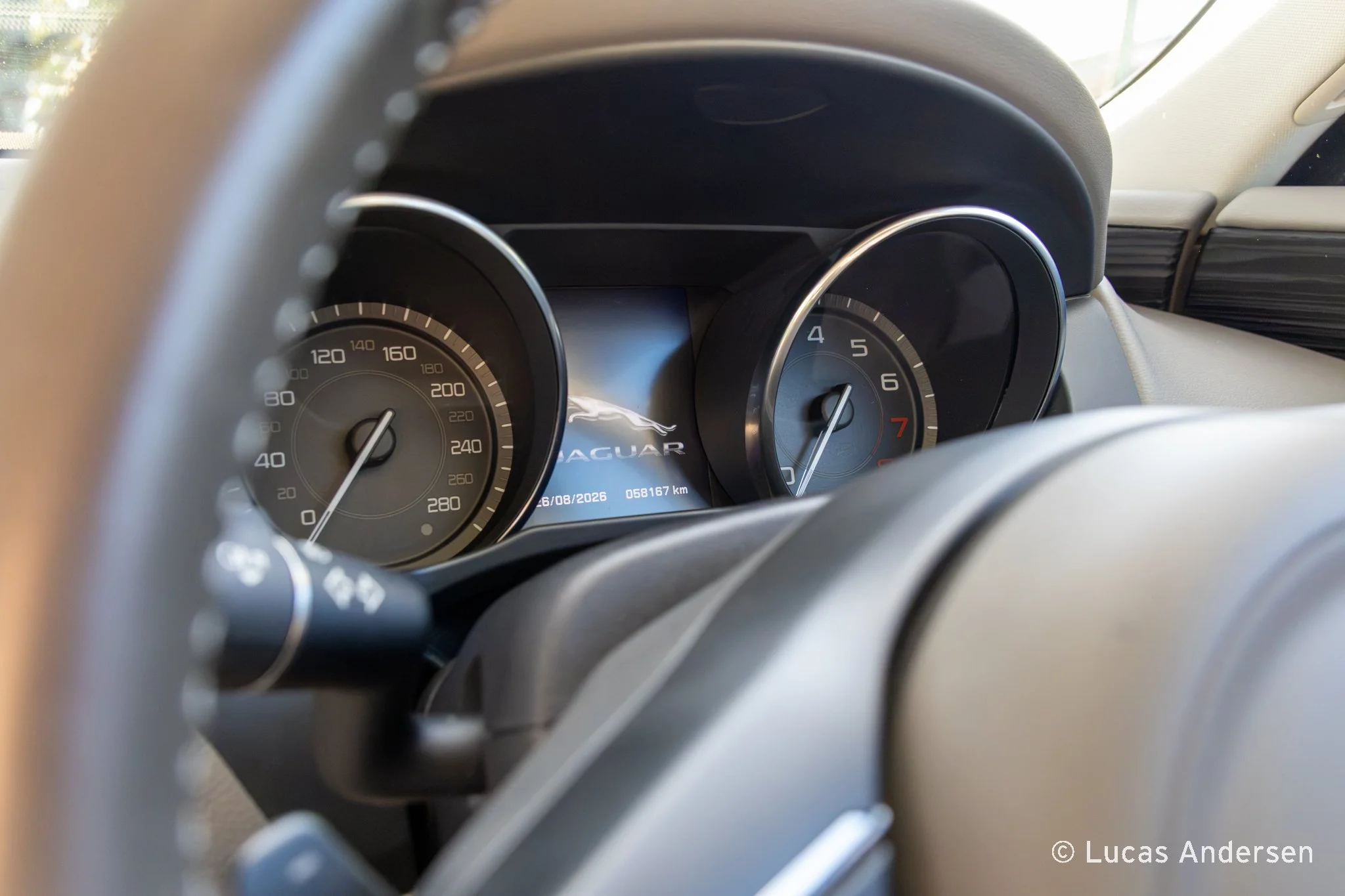 The dashboard of a Jaguar vehicle, showing speed and tachometer gauges, with the Jaguar logo and a digital display in the center.