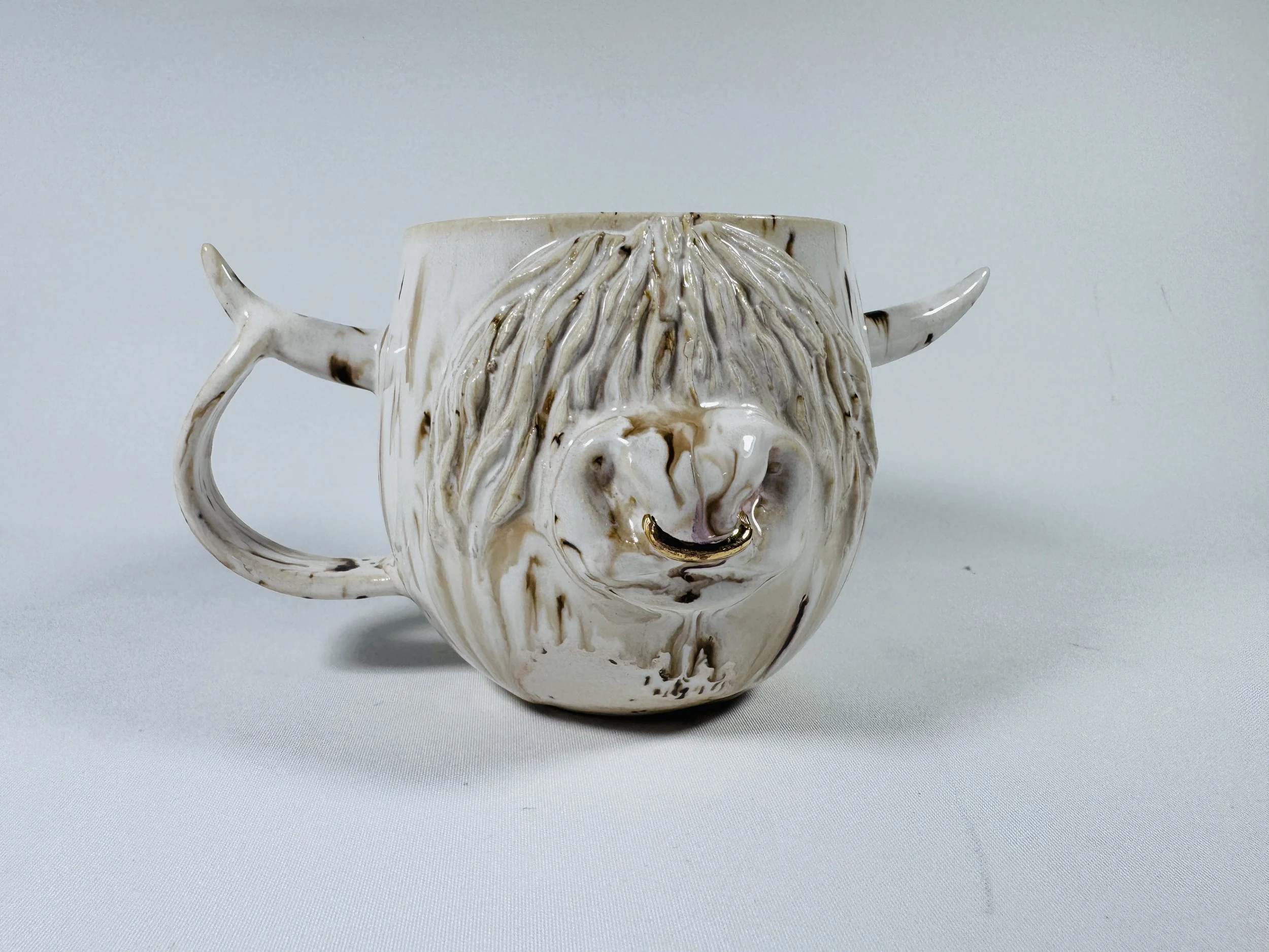 Ceramic Himalayan Cow mug decorated with gold and white glaze, featuring a 24 carat gold nose ring.