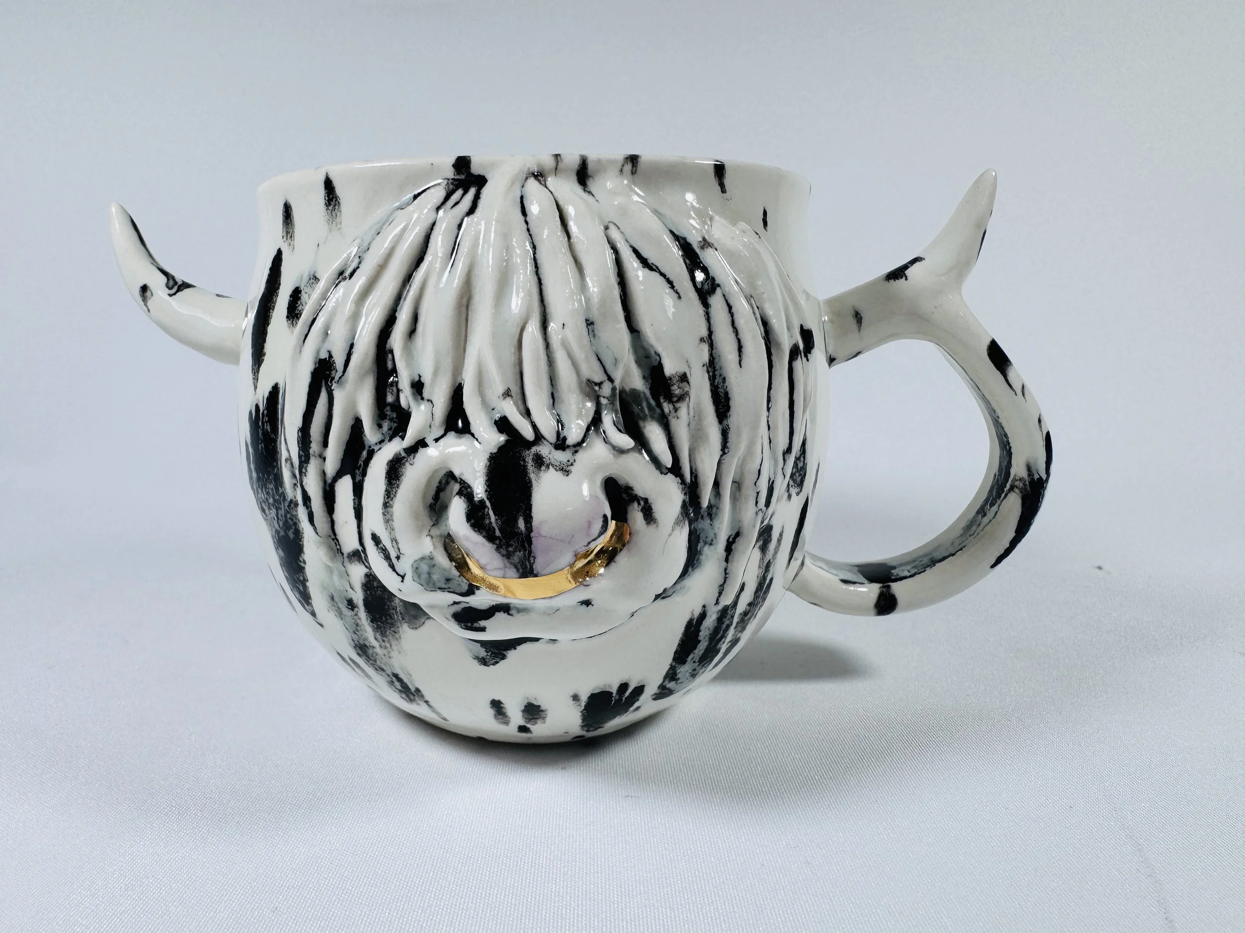 Ceramic Himalayan Cow mug decorated with black and white glaze, featuring a 24 carat gold nose ring.