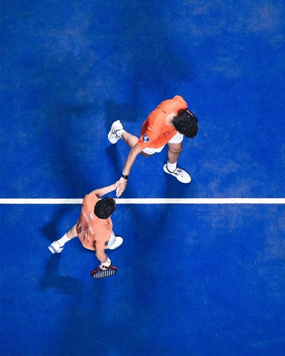 Deux jeunes hommes sur un court de tennis en train de se serrer la main après un match.