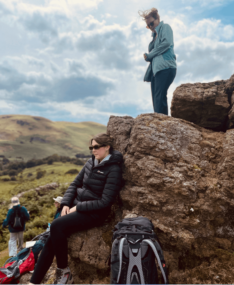 2 people on an expedition taking a break from walking, admiring the view and exploring the rocks.