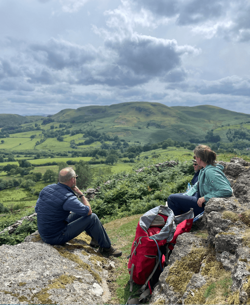 3 people on an expedition taking a break from walking and admiring the view.