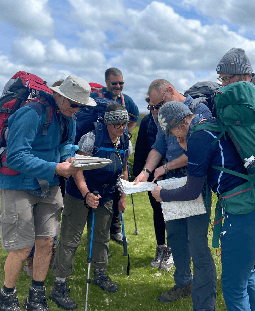 A group of people smiling, looking at maps and planning their route to walk.