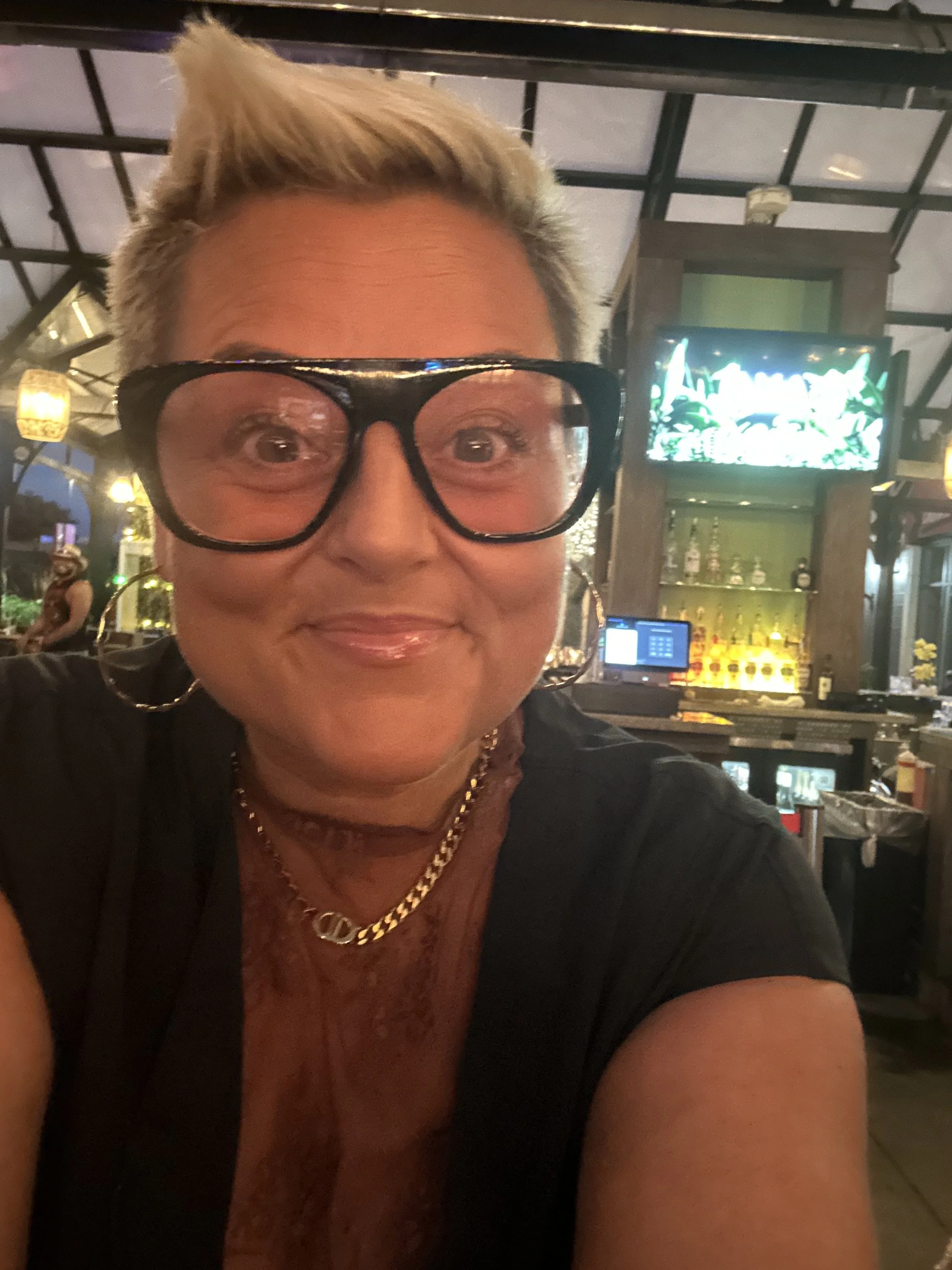 Adina O'Neal in glasses and black capped sleeve top smiling .