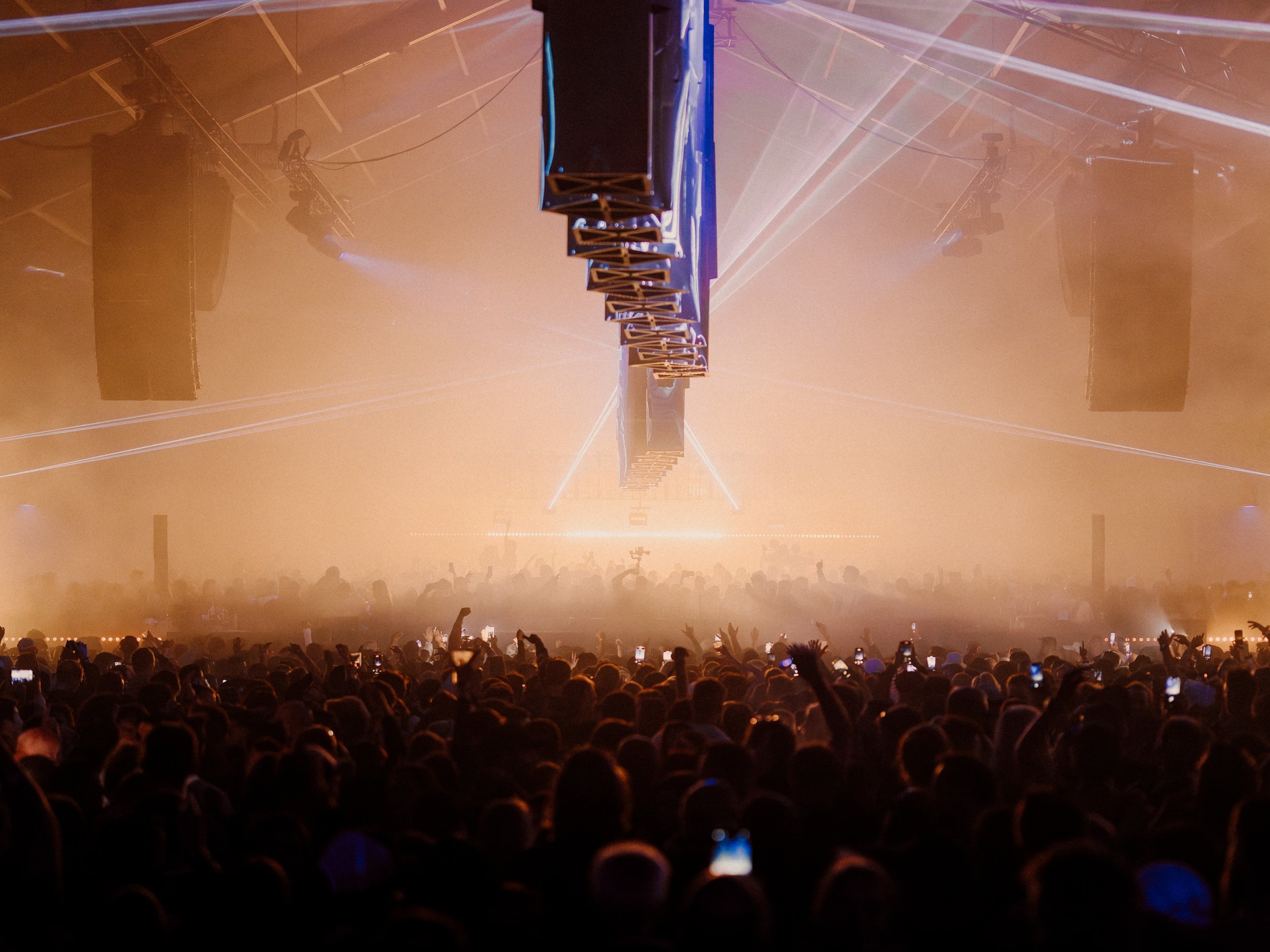 Crowd viewing a concert with stage lighting and smoke in the air. Reflecting Bodies VI Voodoo Village Belgium Scenography art installation light installation Simone Smelt Lumus Instruments Festival main stage