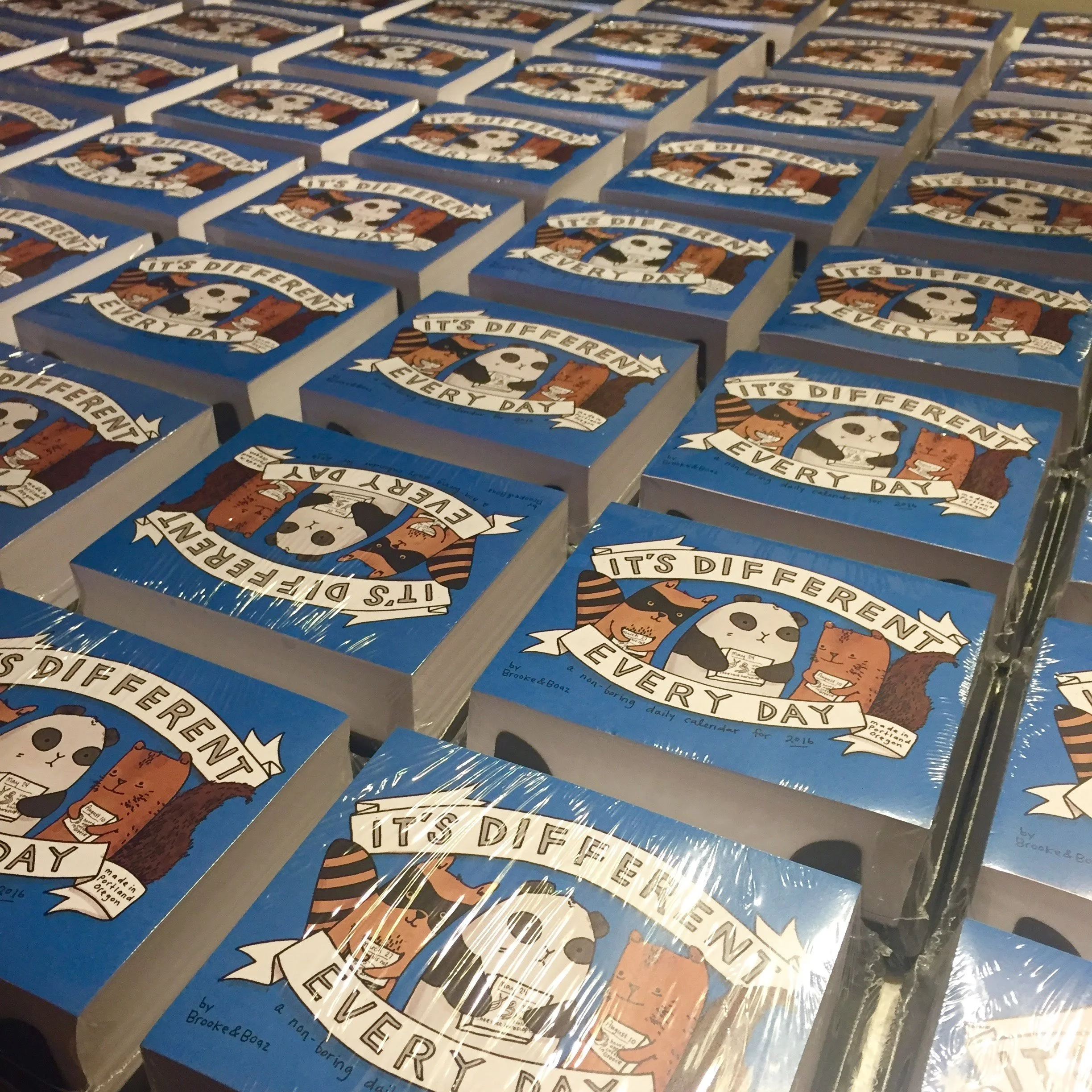 Stacks of books titled "It's Different Every Day" with cartoon illustrations of animals on the cover.