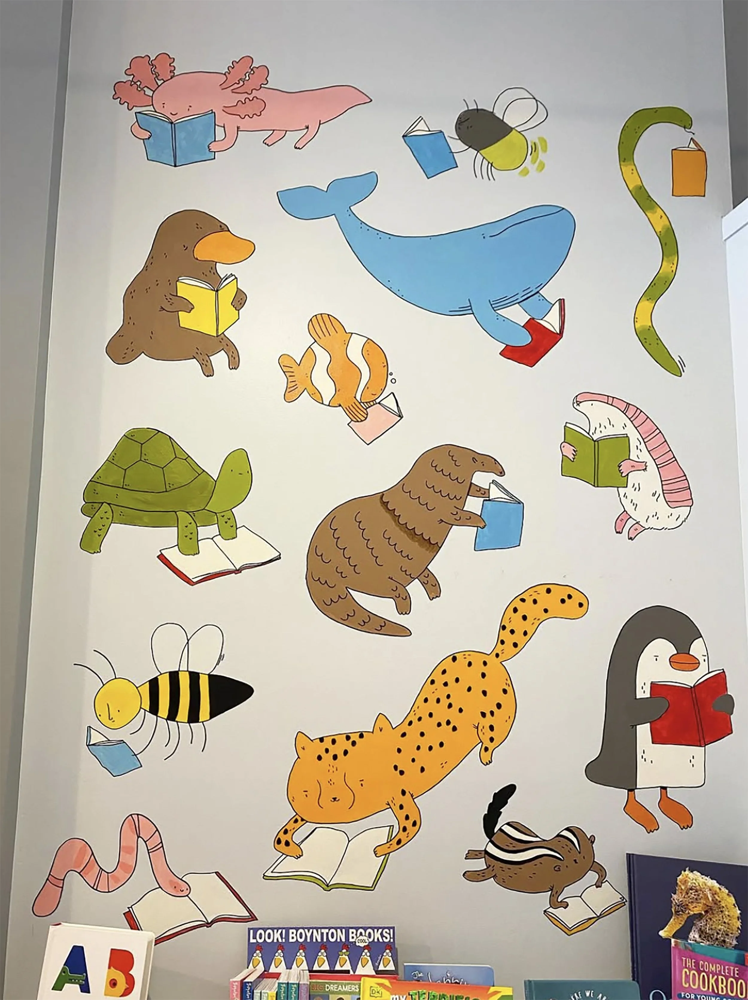 Cartoon animals reading books, including an axolotl, platypus, whale, firefly, turtle, fish, pangolin, anteater, cheetah, bee, snake, penguin, skunk, and worm. Books on shelf below. "Look! Boynton Books!" sign visible.