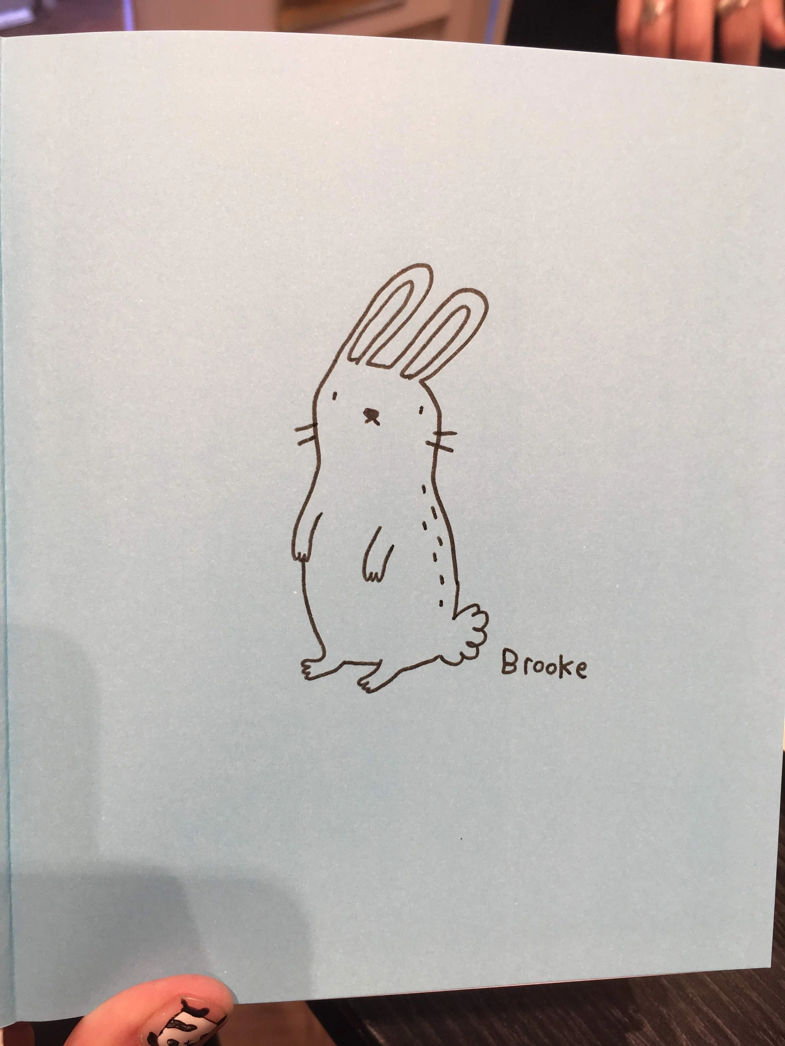 Simple black line drawing of a standing rabbit on a light blue background, labeled "Brooke."