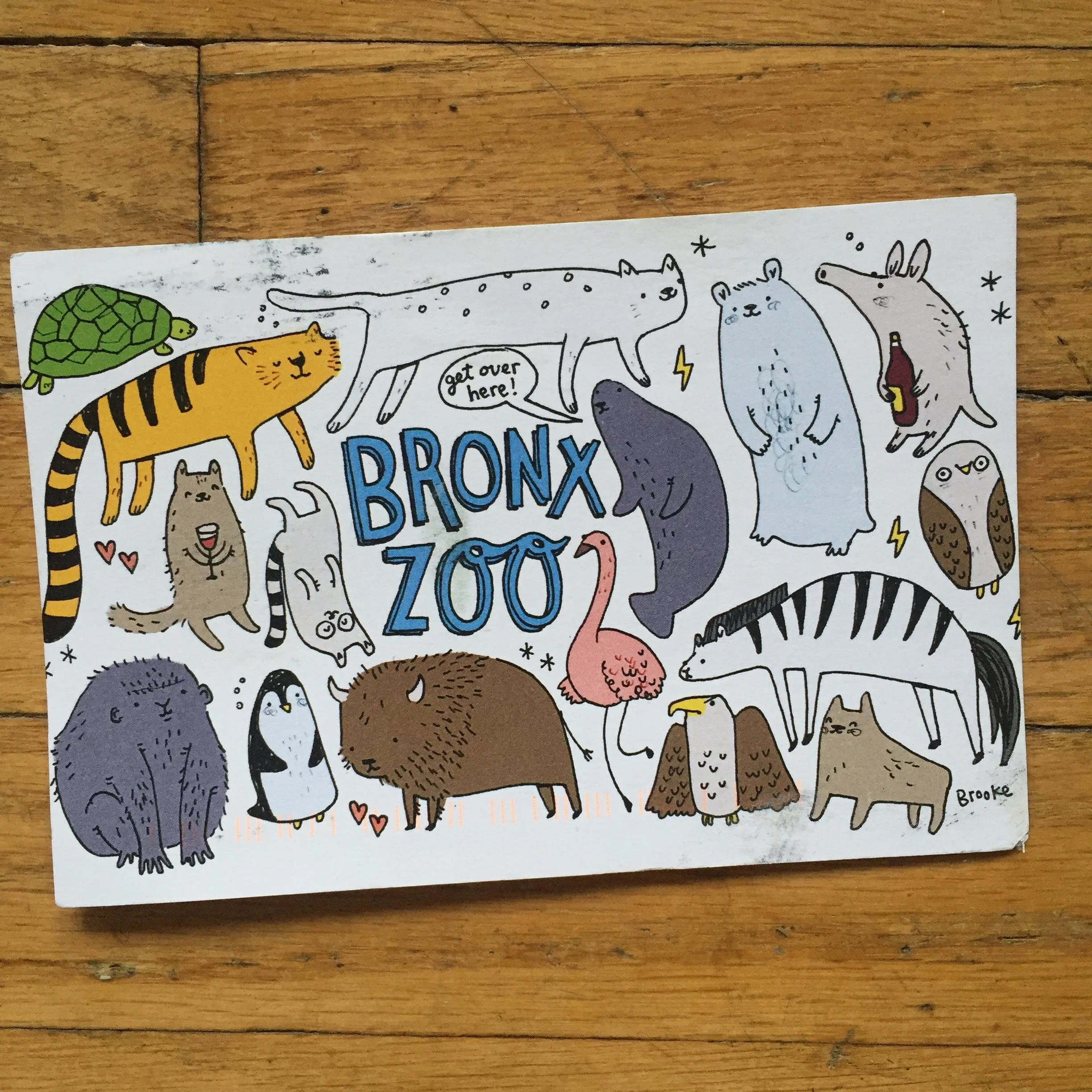 Illustrated postcard with various cartoon animals and the words 'Bronx Zoo'. Animals include a tiger, polar bear, penguin, flamingo, aardvark, turtle, and others, all with whimsical designs.