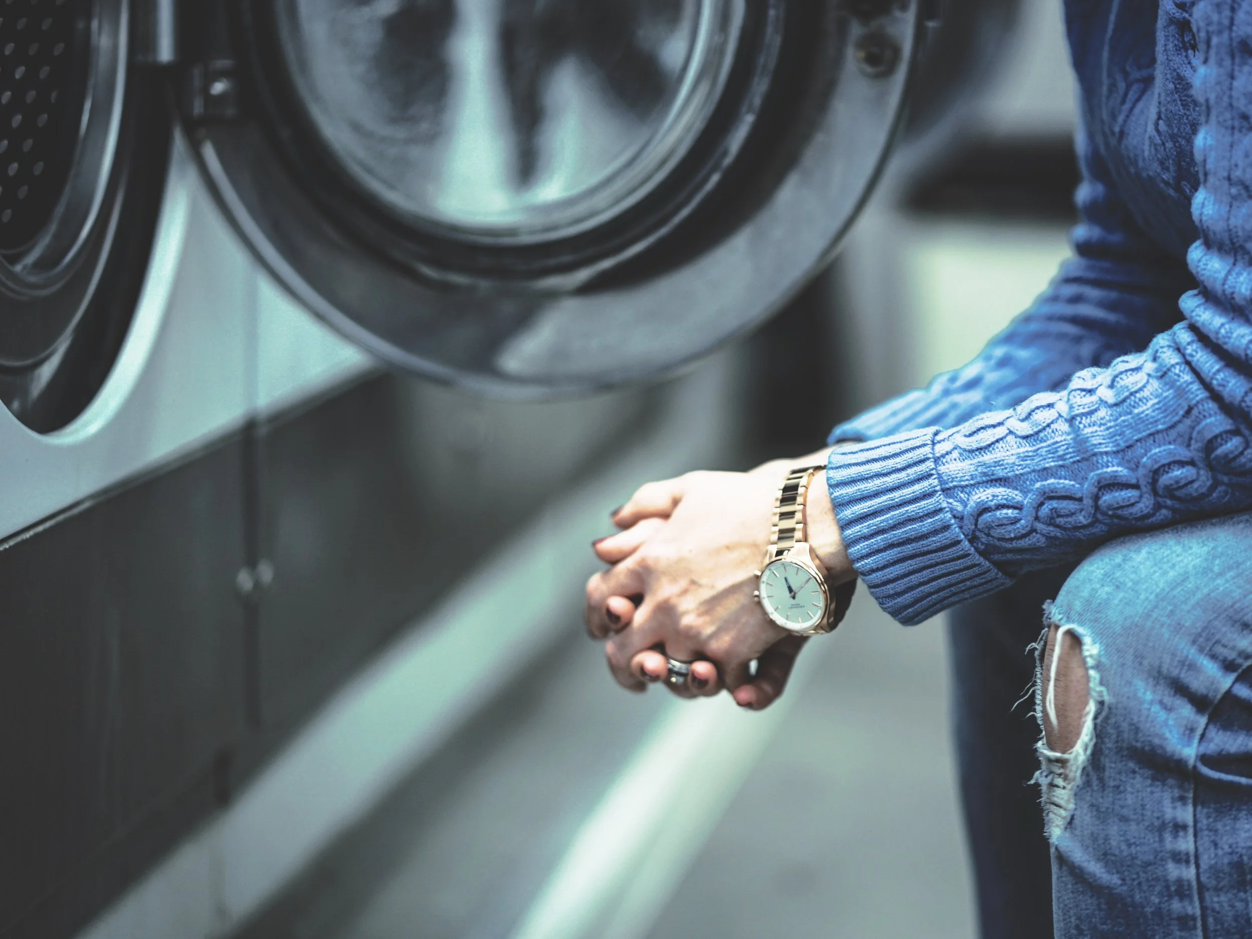 An image of a a watch on a wrist in a laundrette..