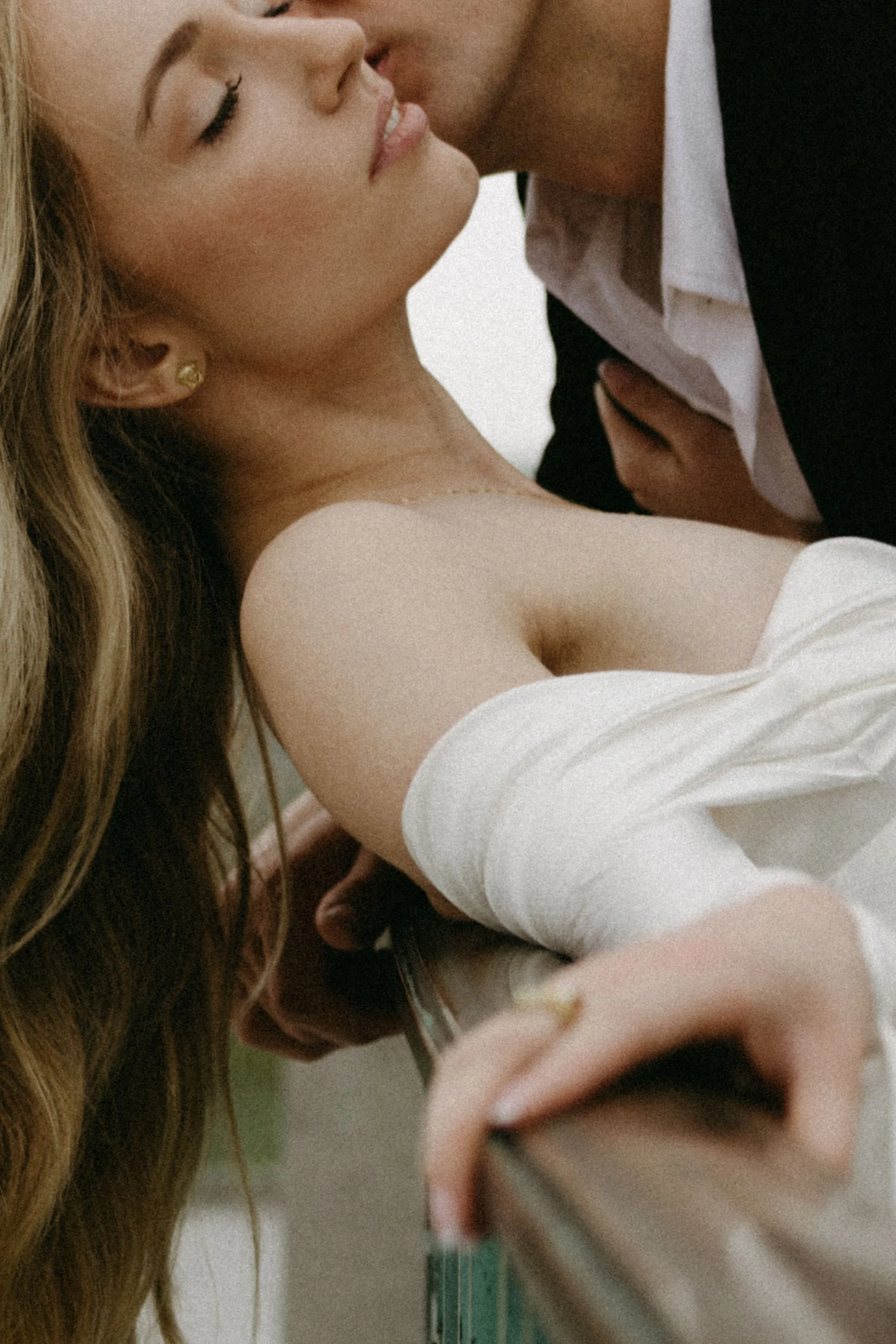 A close-up of a romantic moment between a man and a woman, with the woman leaning back and the man kissing her on the lips, her eyes closed, with soft lighting.