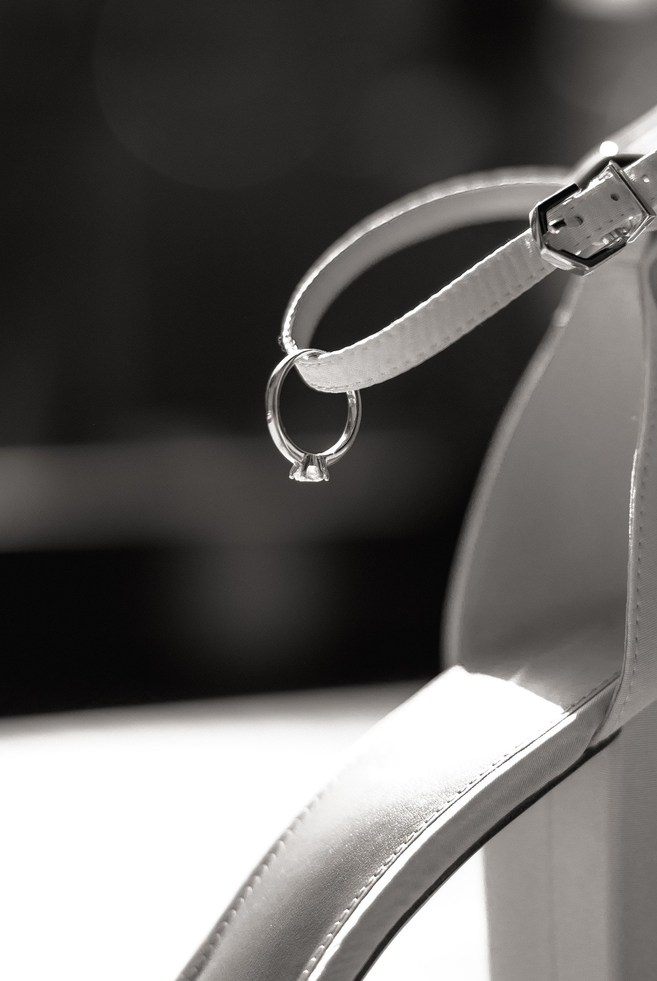 Detailaufnahme eines Verlobungsringes, gehangen an den Riemen des Brautschuhs.