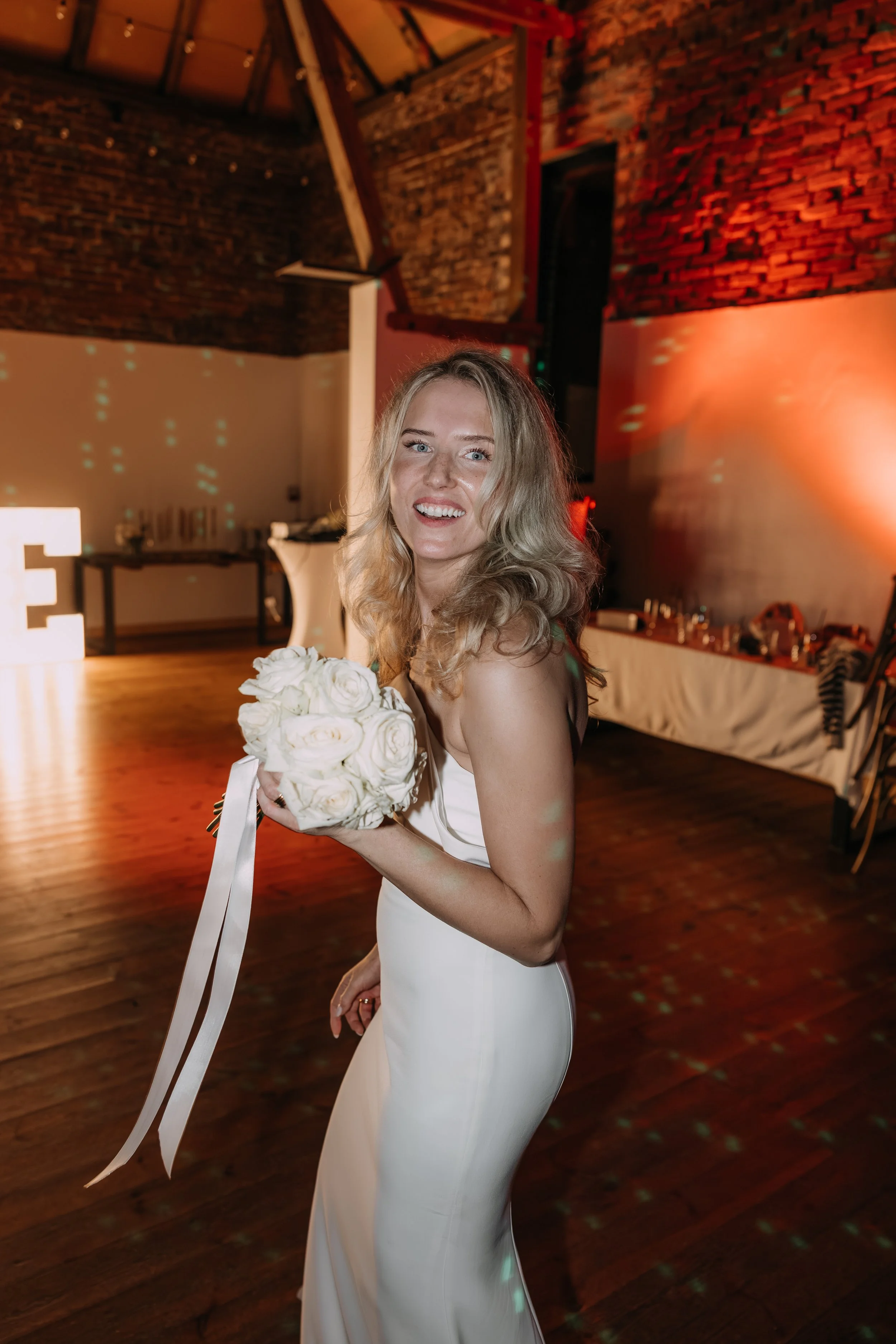 Eine Braut mit Brautstrauß vor dem Straußwurf, sie blickt zurück zu ihren Gästen.