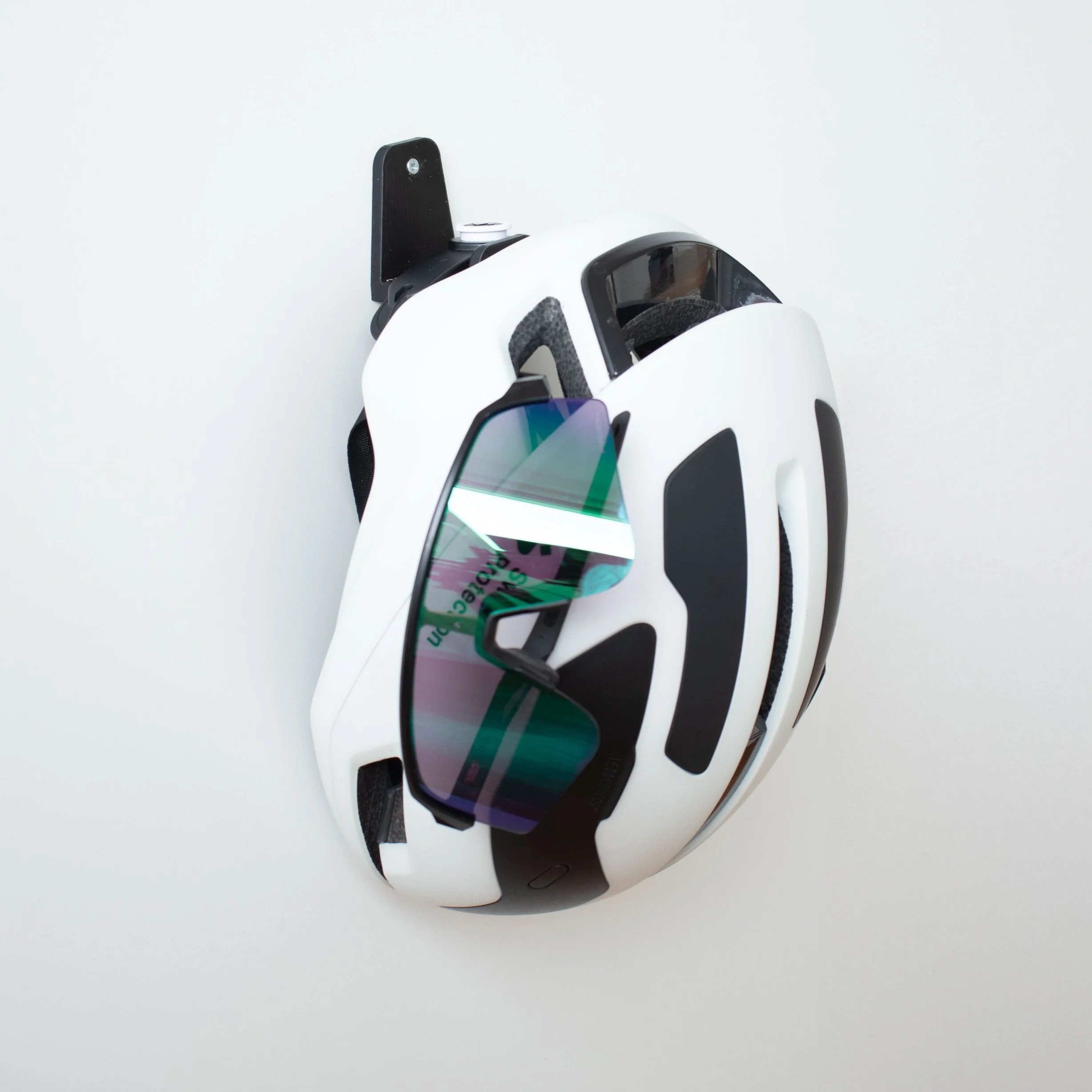 Casque de vélo Sweet Protection et lunettes cyclisme Oakley accrochés à un support mural design
