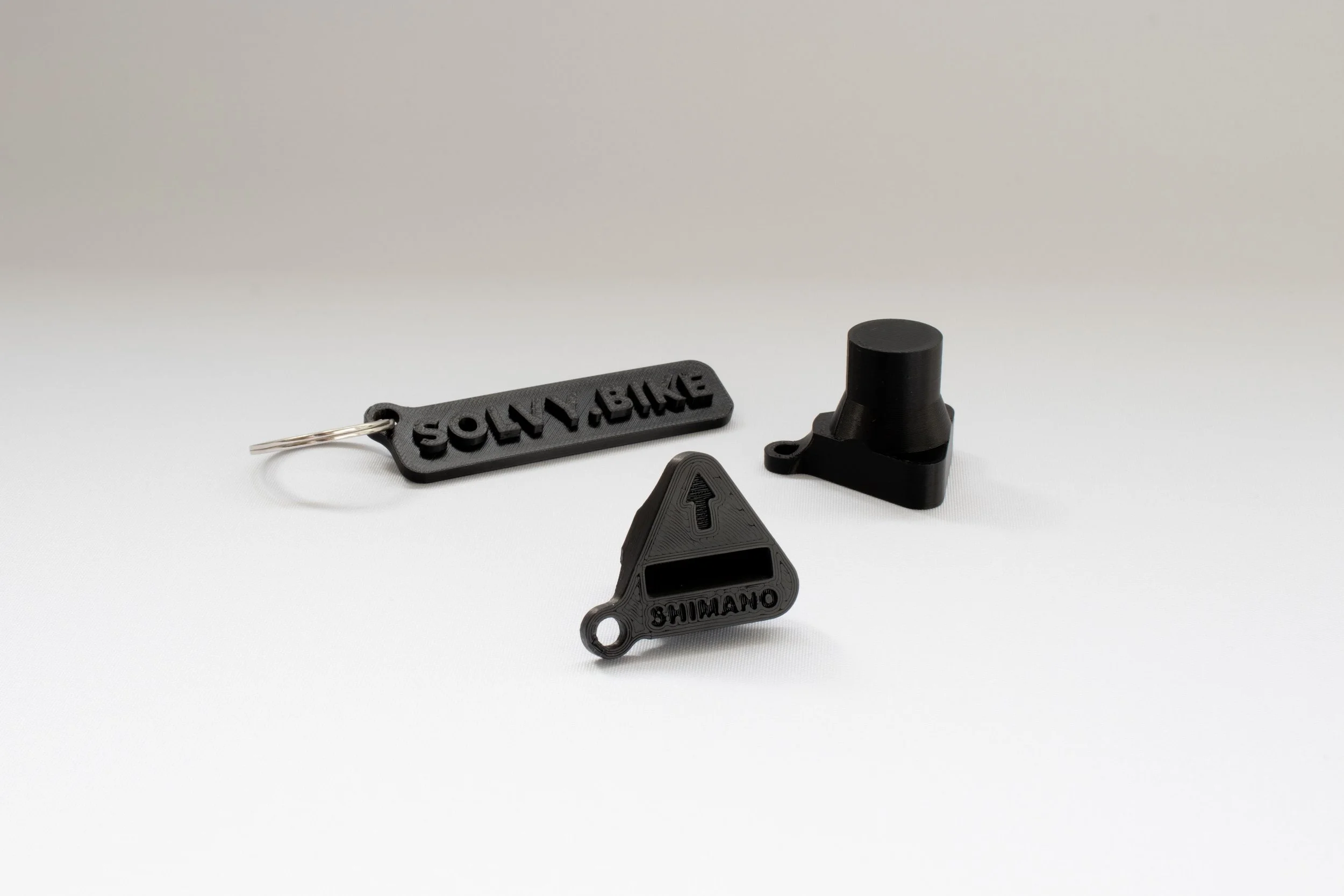 Trois outils de mesure de hauteur de selle pour cyclistes en plastique noir de différentes formes, avec inscriptions "Shimano" et "SRAM".