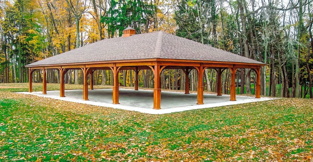 A wooden pavilion in a park surrounded by trees with autumn leaves