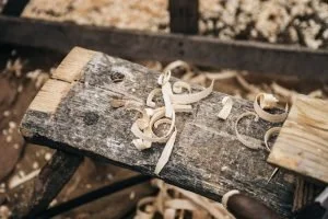 Close-up of a weathered wooden workbench with wood shavings on top.