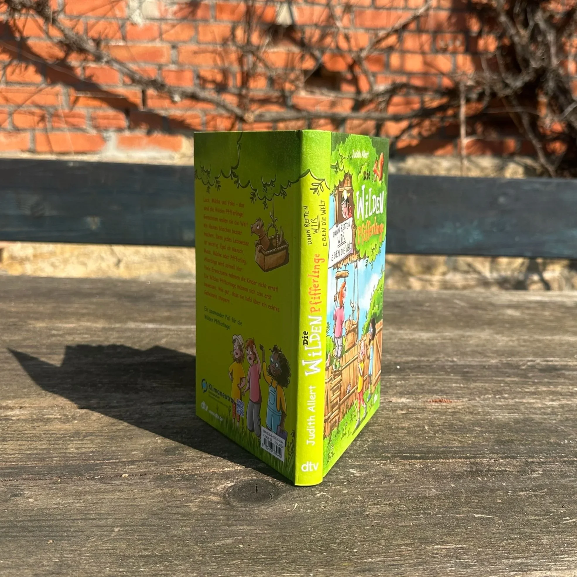 Das Buch "Die Wilden Pfifferlinge - Dann retten wir eben die Welt." steht hochkant auf einem Tisch.