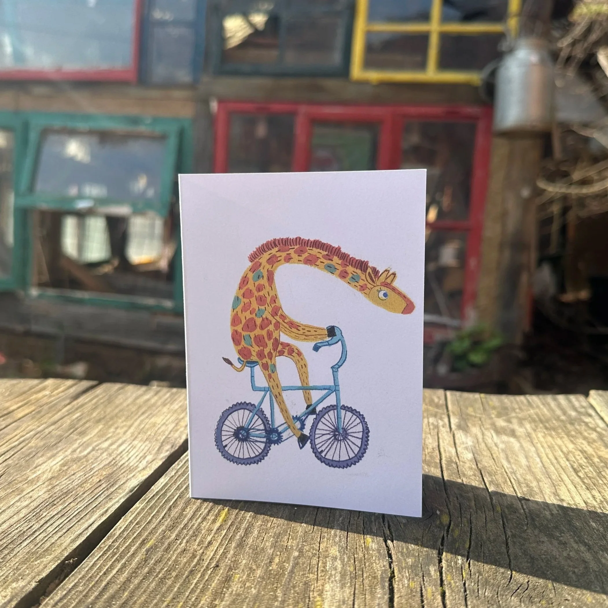 Ein Foto der Klappkarte "Das Fräulein fährt Rad". Darauf eine Giraffe auf einem Fahrrad.