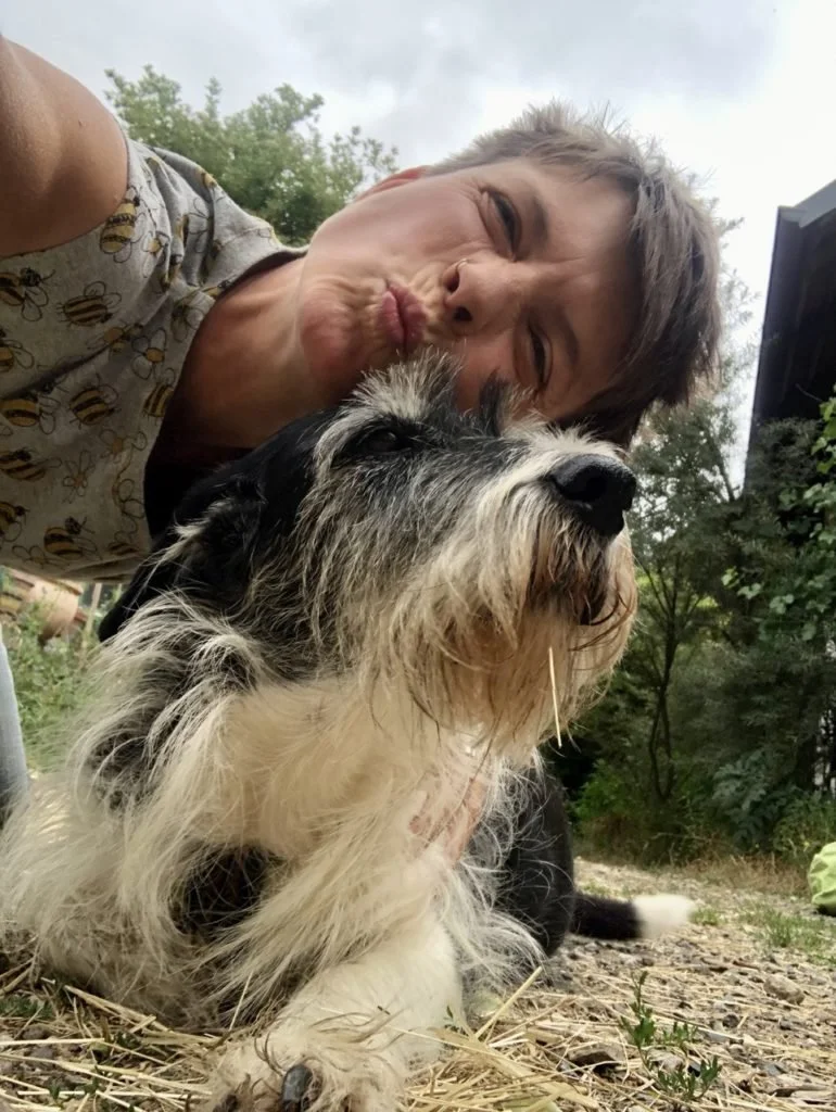 Das Bild zeigt Judith und ihren Hund Alma. Eine schwarz-weiße Mischlingshündin.