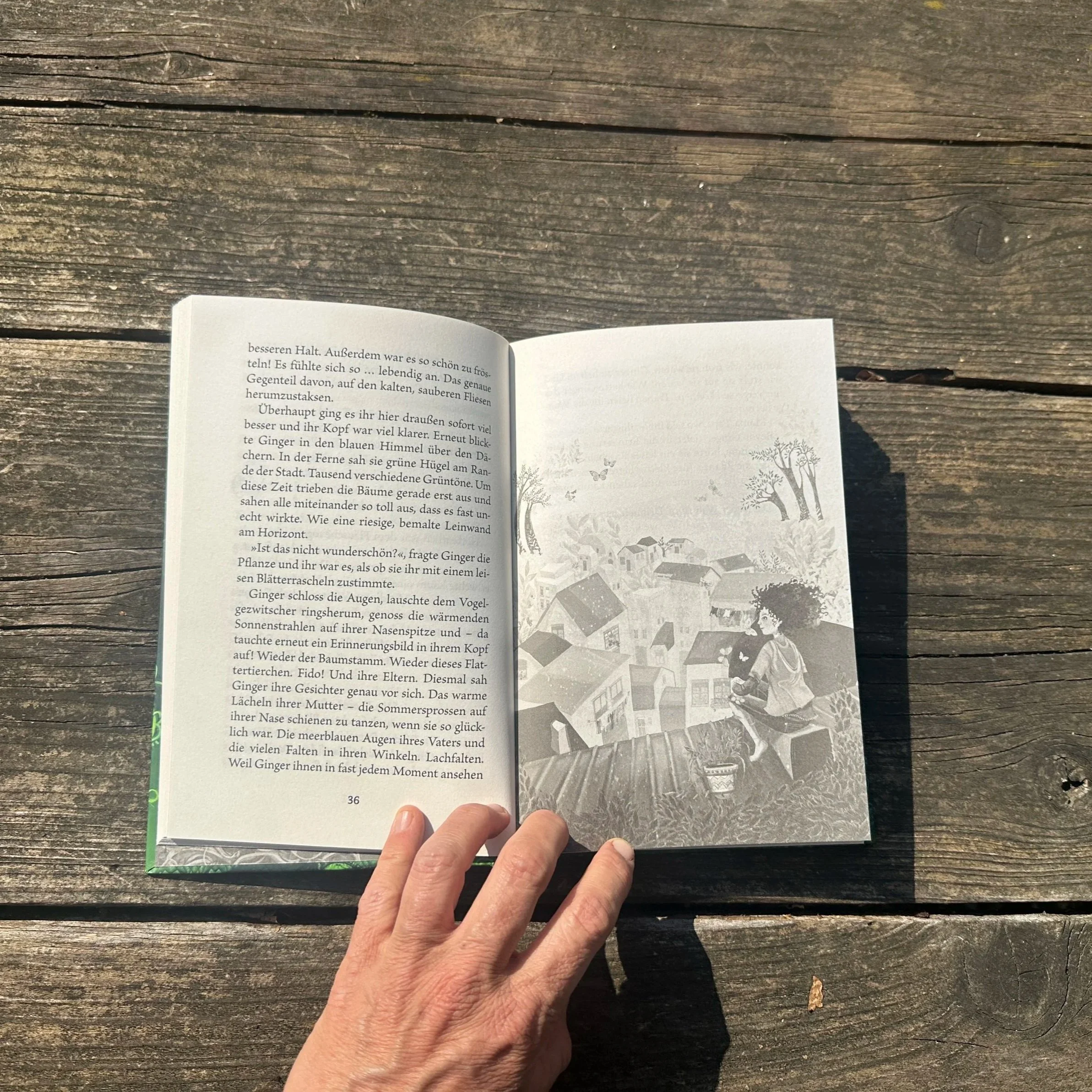 Das Buch "Ginger und die Bibliothek der magischen Pflanzen" liegt aufgeschlagen auf einem Tisch.