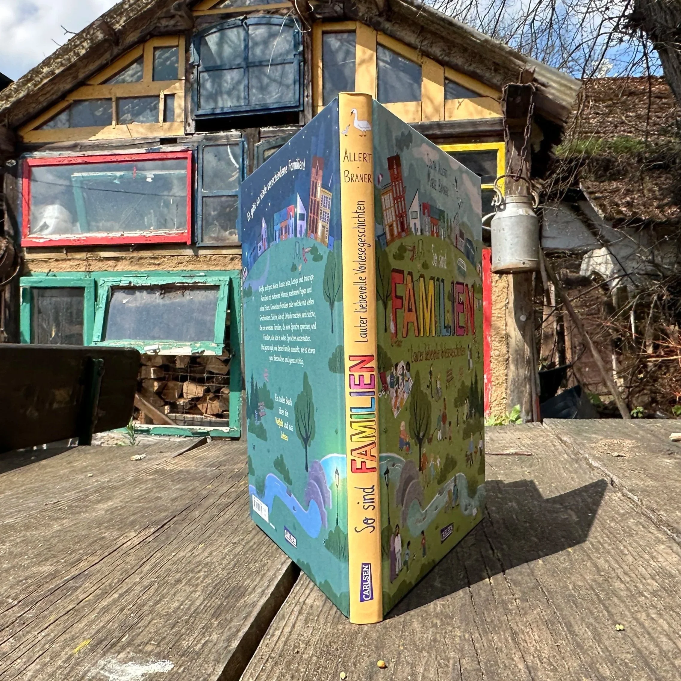 Das Buch "So sind Familien" steht aufgeschlagen auf einem Holztisch.